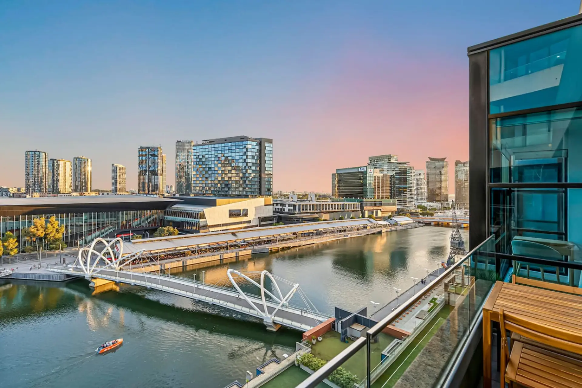 A stunning balcony outlook over modern architecture and calm waterfront scenery, perfect for enjoying sunrise or sunset above the city.
