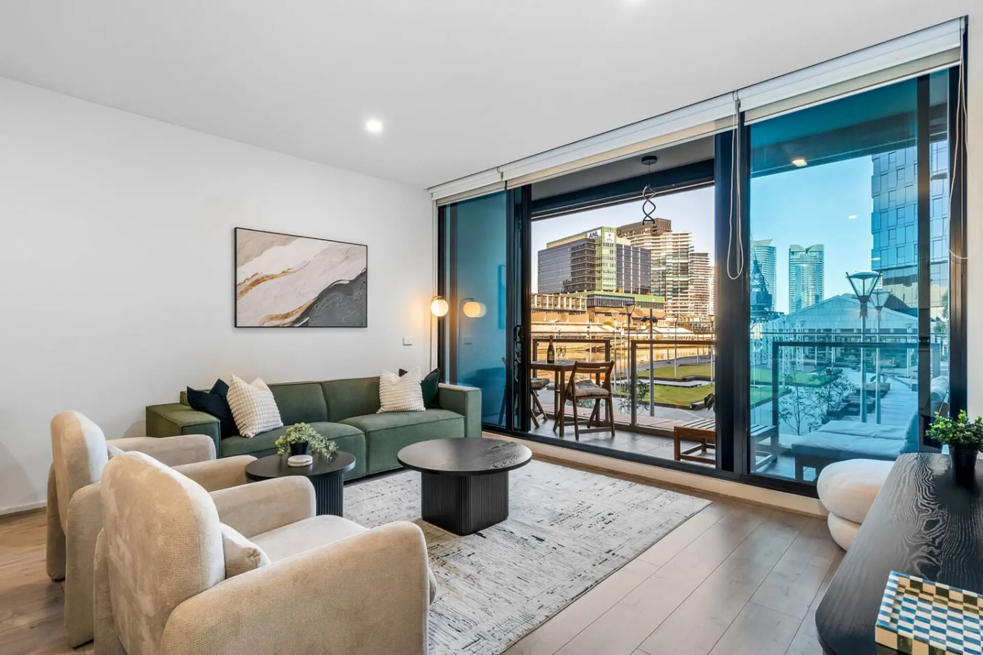Bright, stylish living room with plush seating, modern coffee tables, and large sliding glass doors leading to a private balcony with stunning city views, perfect for relaxing and enjoying the skyline.