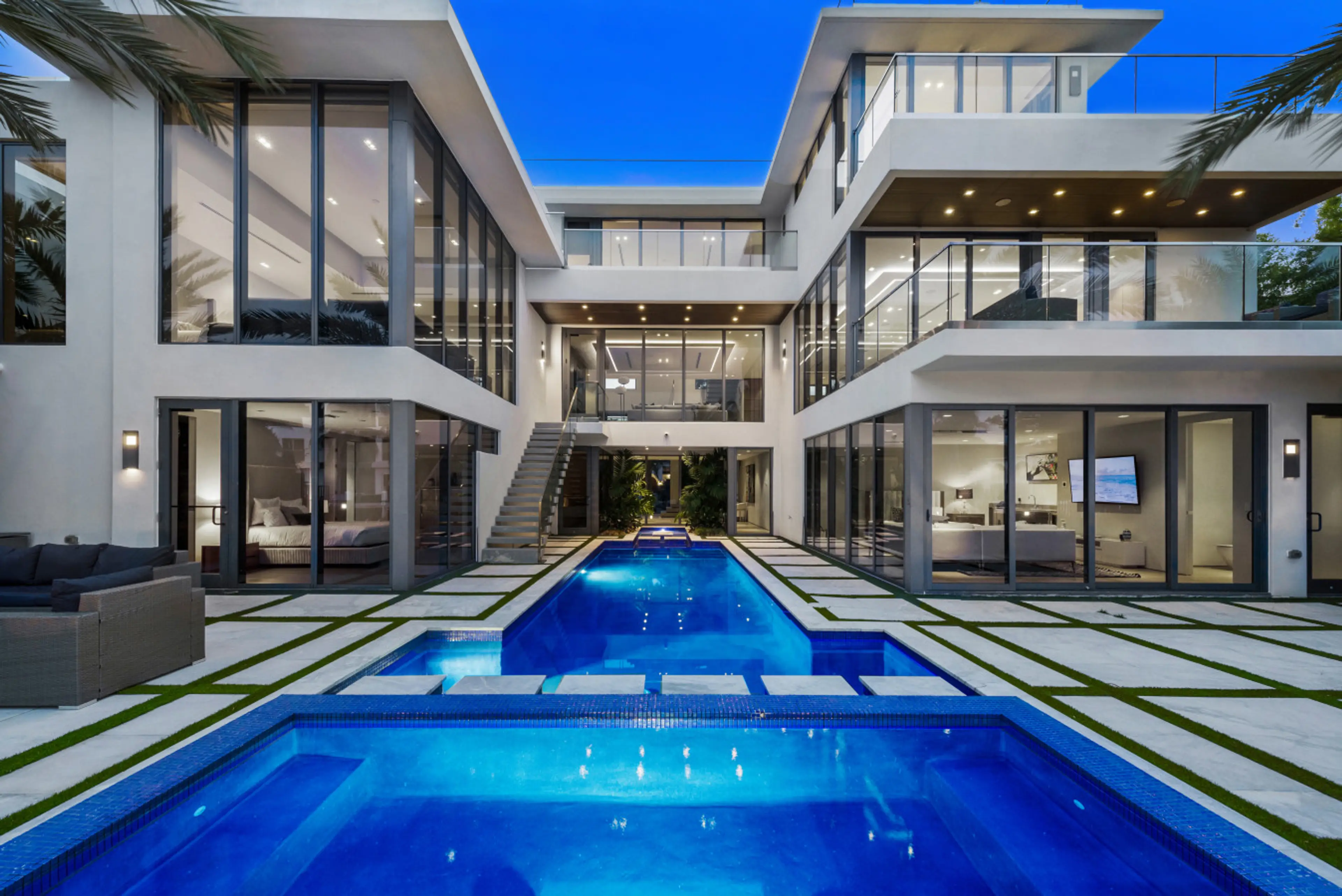 Exterior view of the villa at dusk, featuring the private, illuminated swimming pool and modern architectural design.