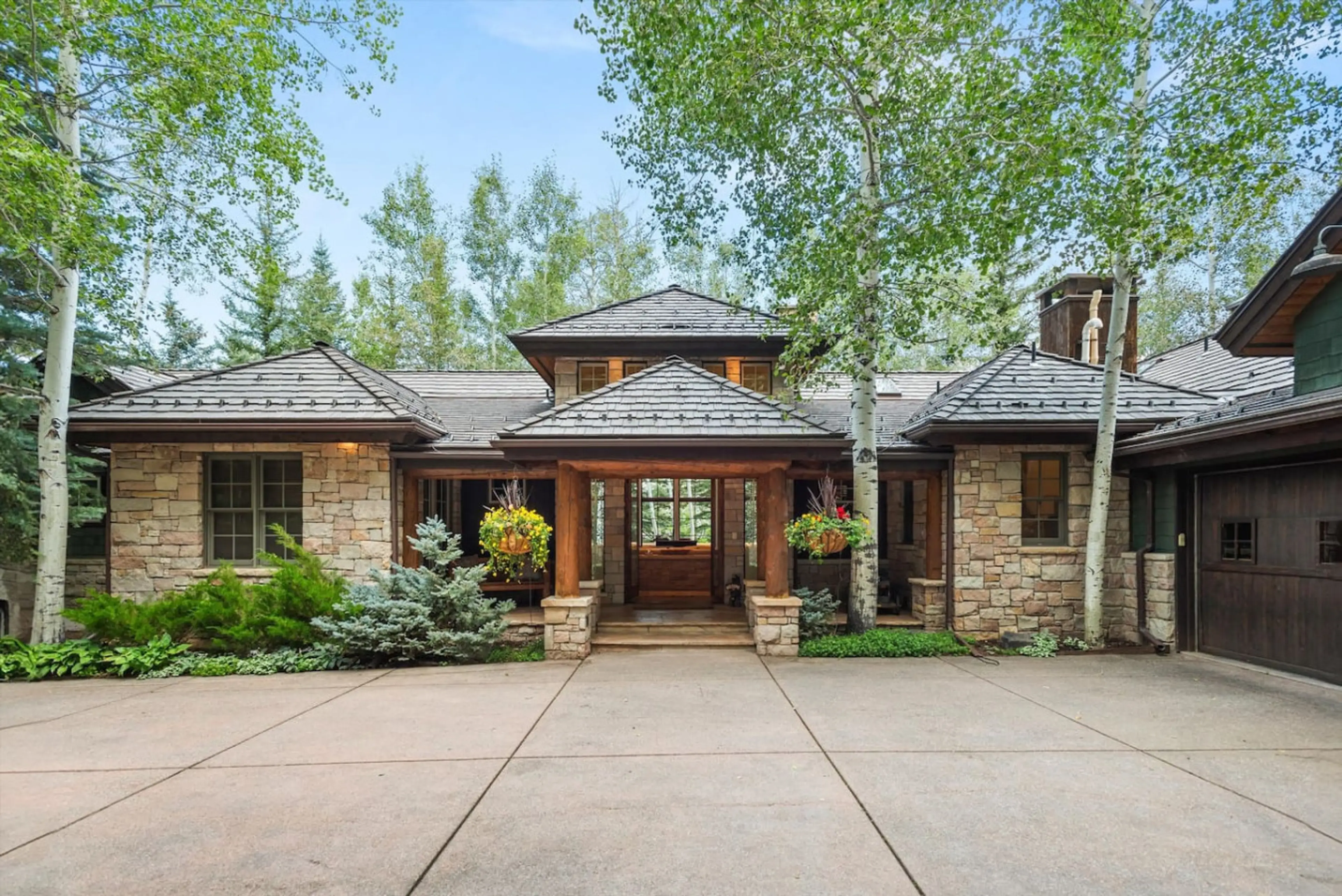 Magnificent estate home with gorgeous curved driveway approach and refined stone construction among towering pine trees