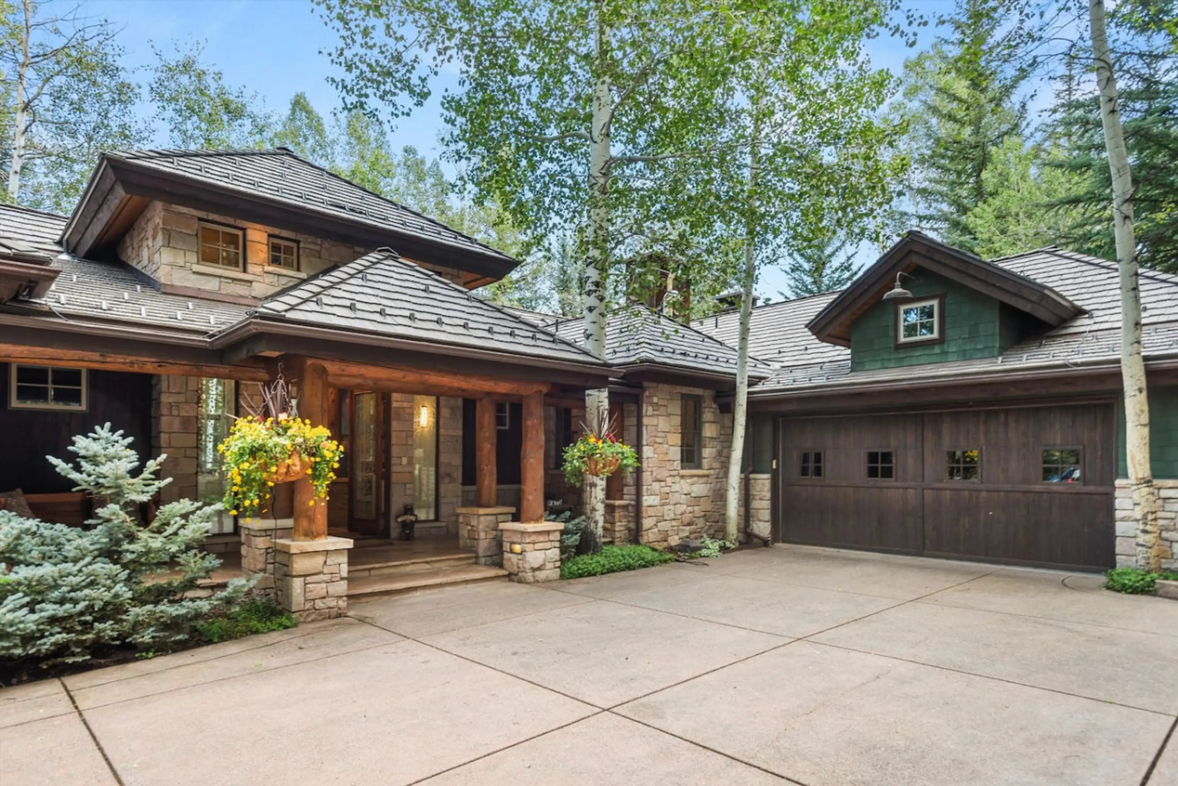 Elegant estate residence with gorgeous stone craftsmanship and sophisticated covered entry surrounded by lush woodland landscape