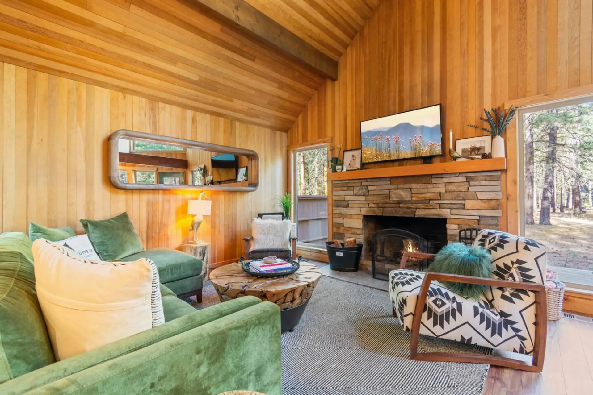 Cozy great room with wood-burning fireplace and forest views