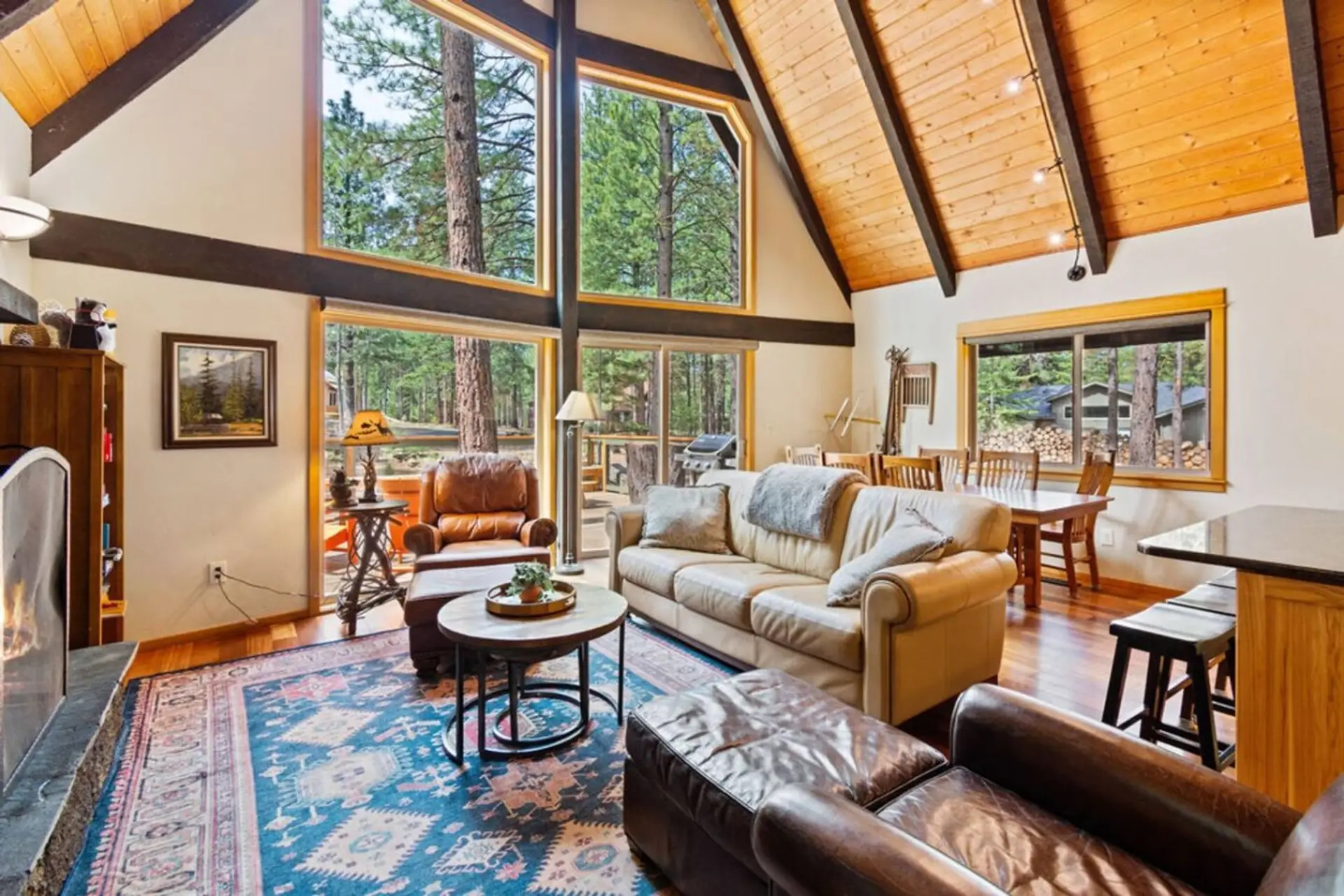 Vaulted A-frame living room with soaring windows, air conditioning, and forest views.