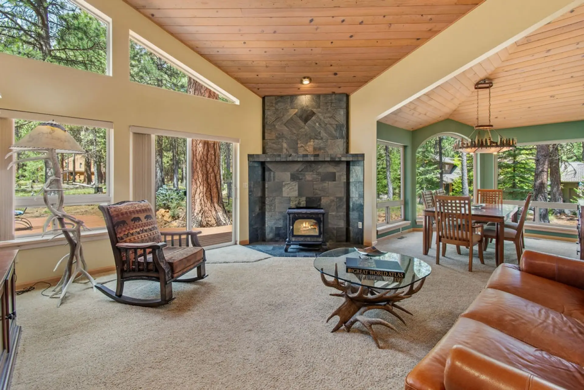 Gather beneath soaring vaulted ceilings, a floor-to-ceiling stone fireplace, and walls of windows in the heart of the home