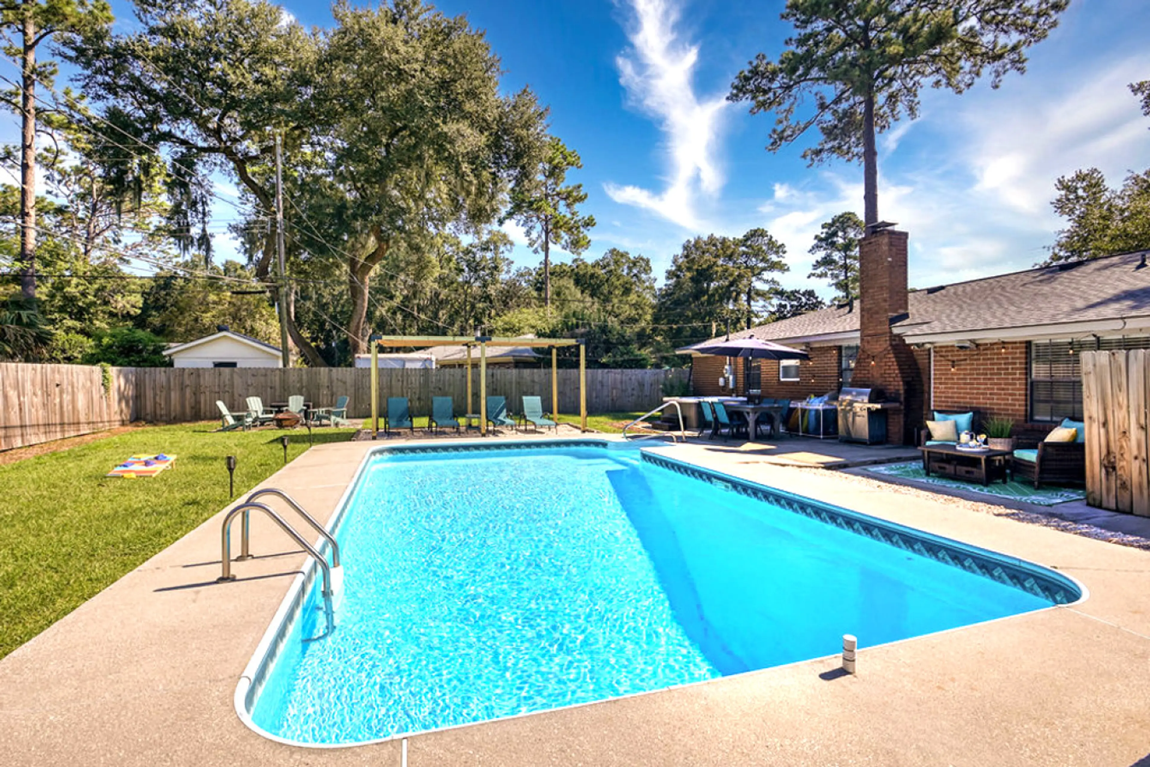 Spacious Backyard Retreat - This fully fenced backyard is perfect for gatherings, featuring a sparkling pool, bubbling hot tub, fire pit lounge, shaded pergola, and plenty of comfortable seating.