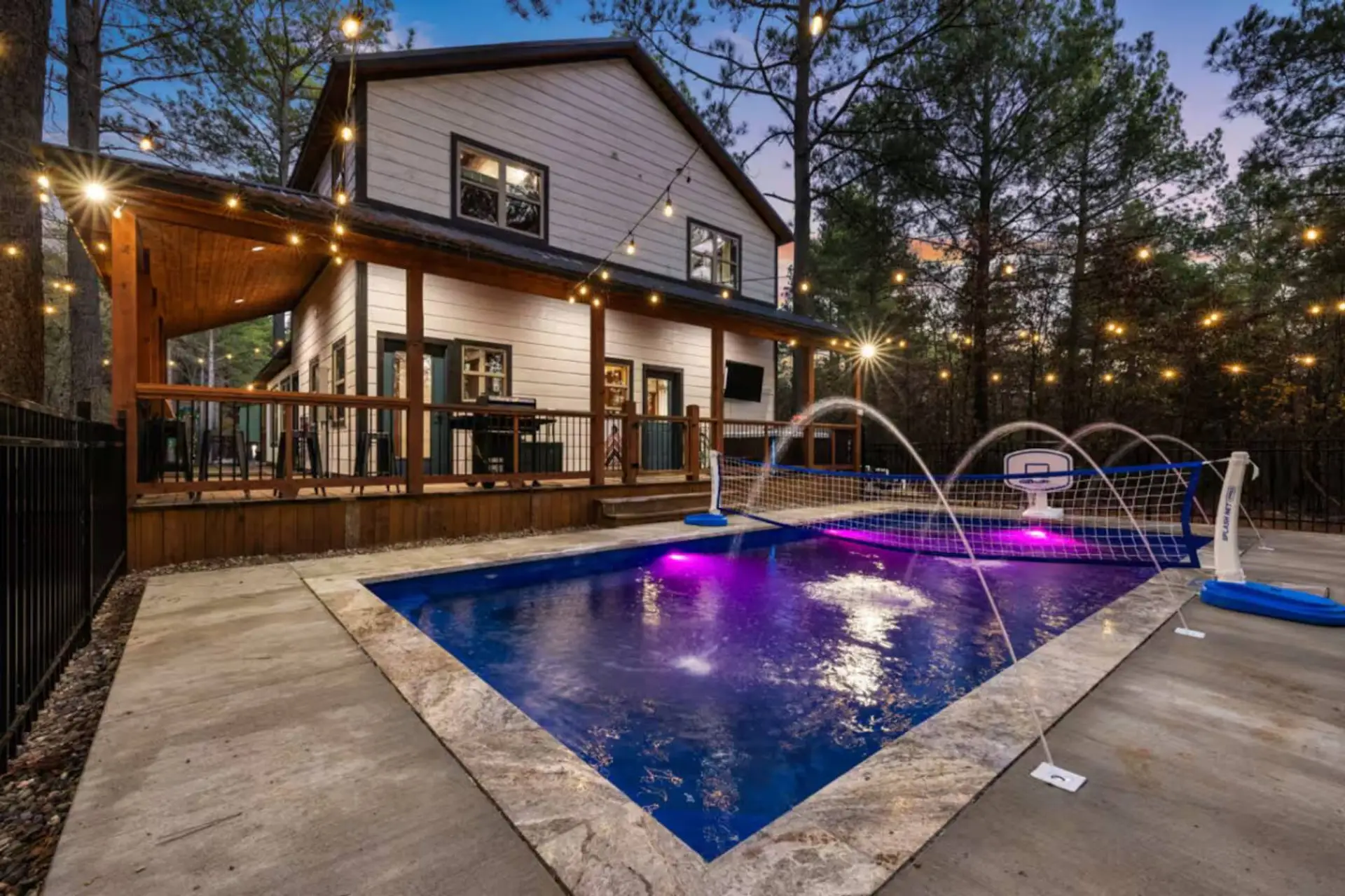 Heated pool glow at Poolside Par‑Tee—fountain jets, color‑changing lights, and the cabin shining behind you. You arrive to a private resort vibe made for late swims, laughter, and a deep exhale.
