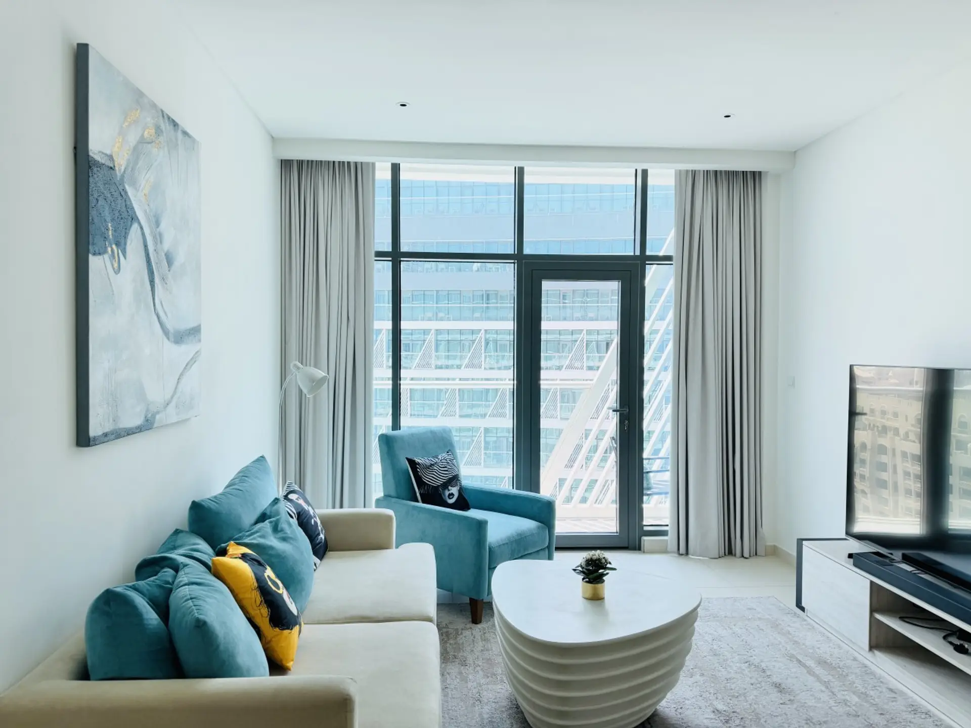 Light living room with cosy chairs, an alongside table and balcony doors.