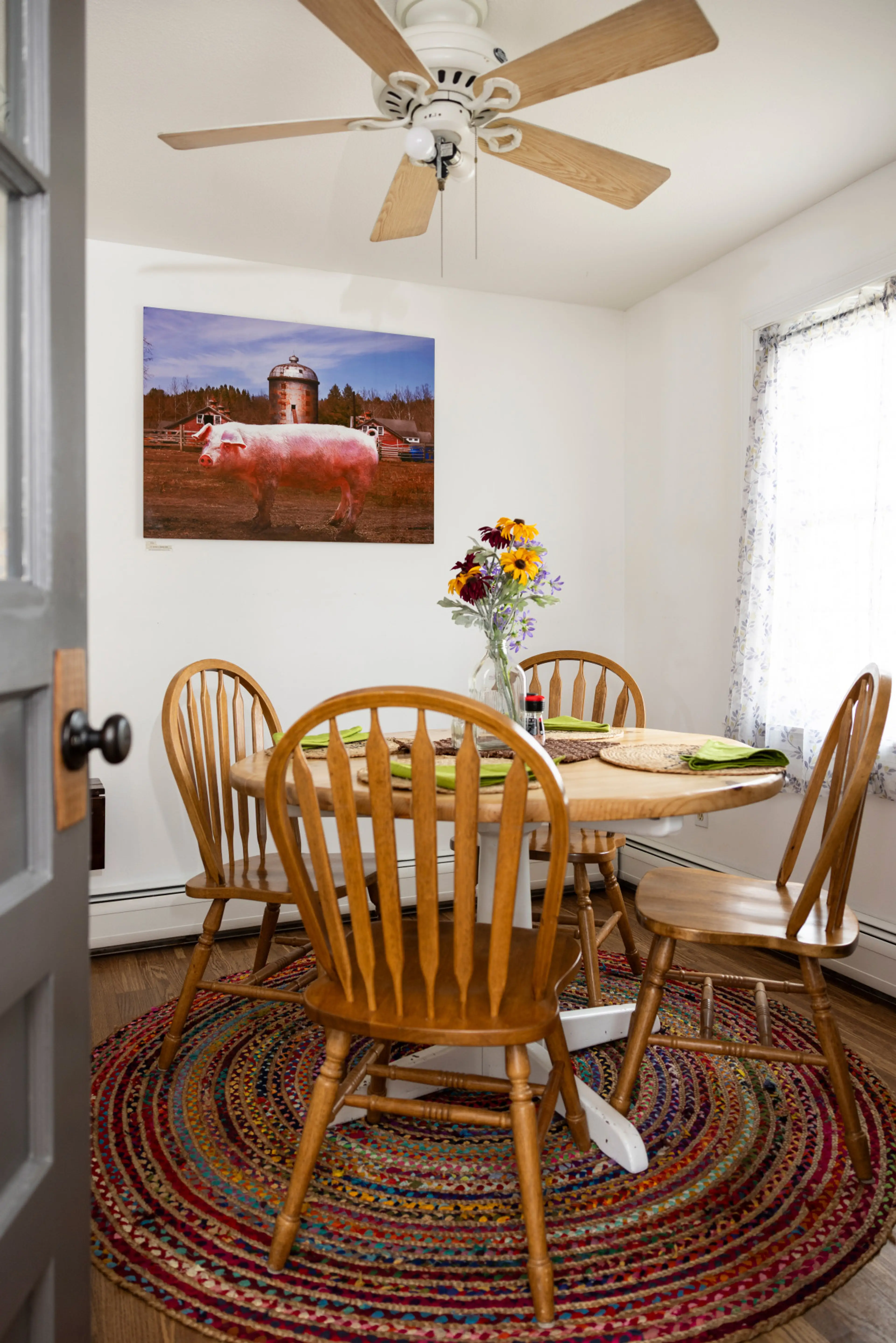 The dining area features a refurbished pine wood farm table and chairs, creating a warm, rustic gathering space. This room also displays additional artwork from Beckerman Photography’s Sustainable Celebrities collection, bringing the farm-inspired theme t