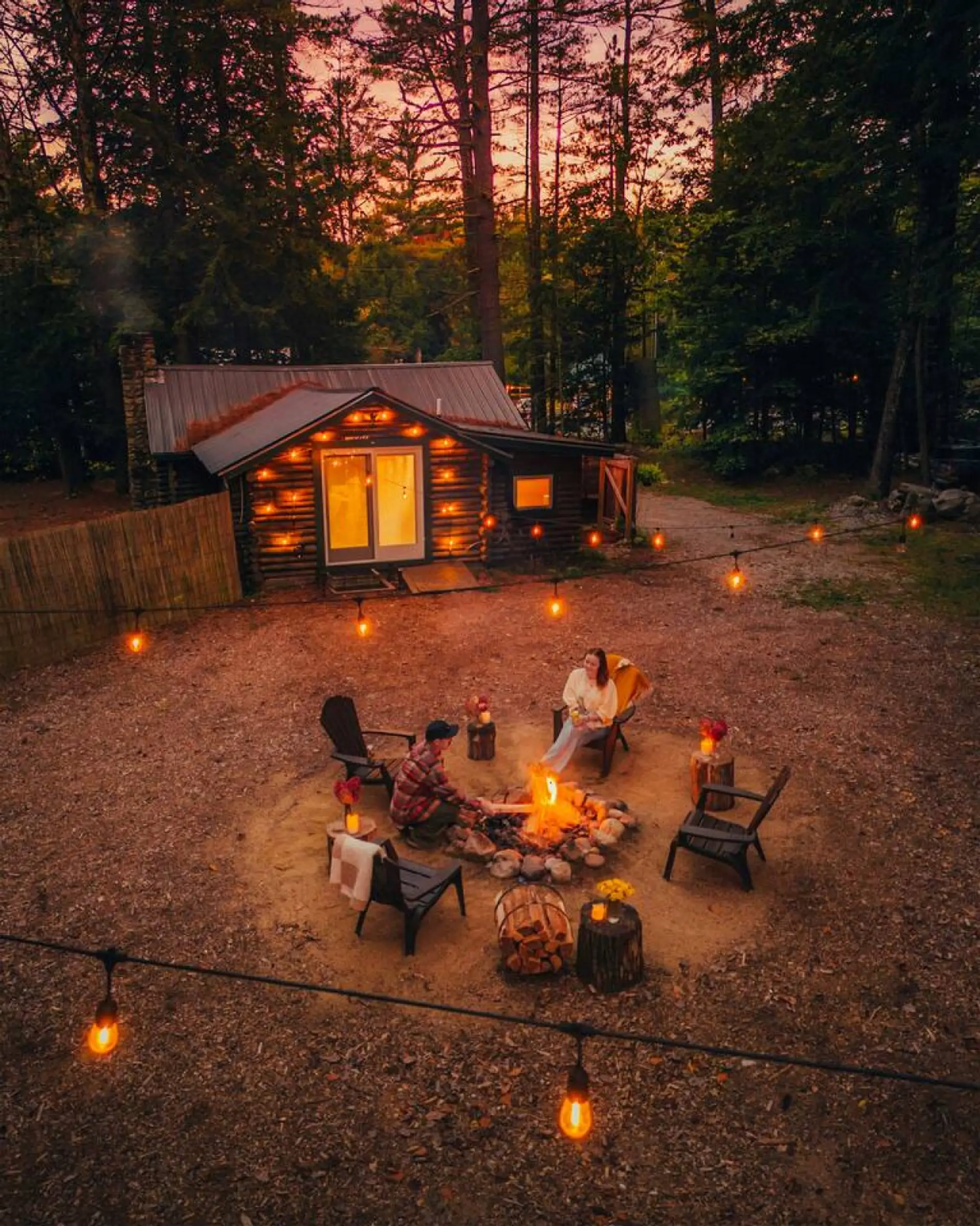 The backyard is private and romantic with a firepit, several seating options, picnic table, string lights, outdoor shower, and forest to explore.