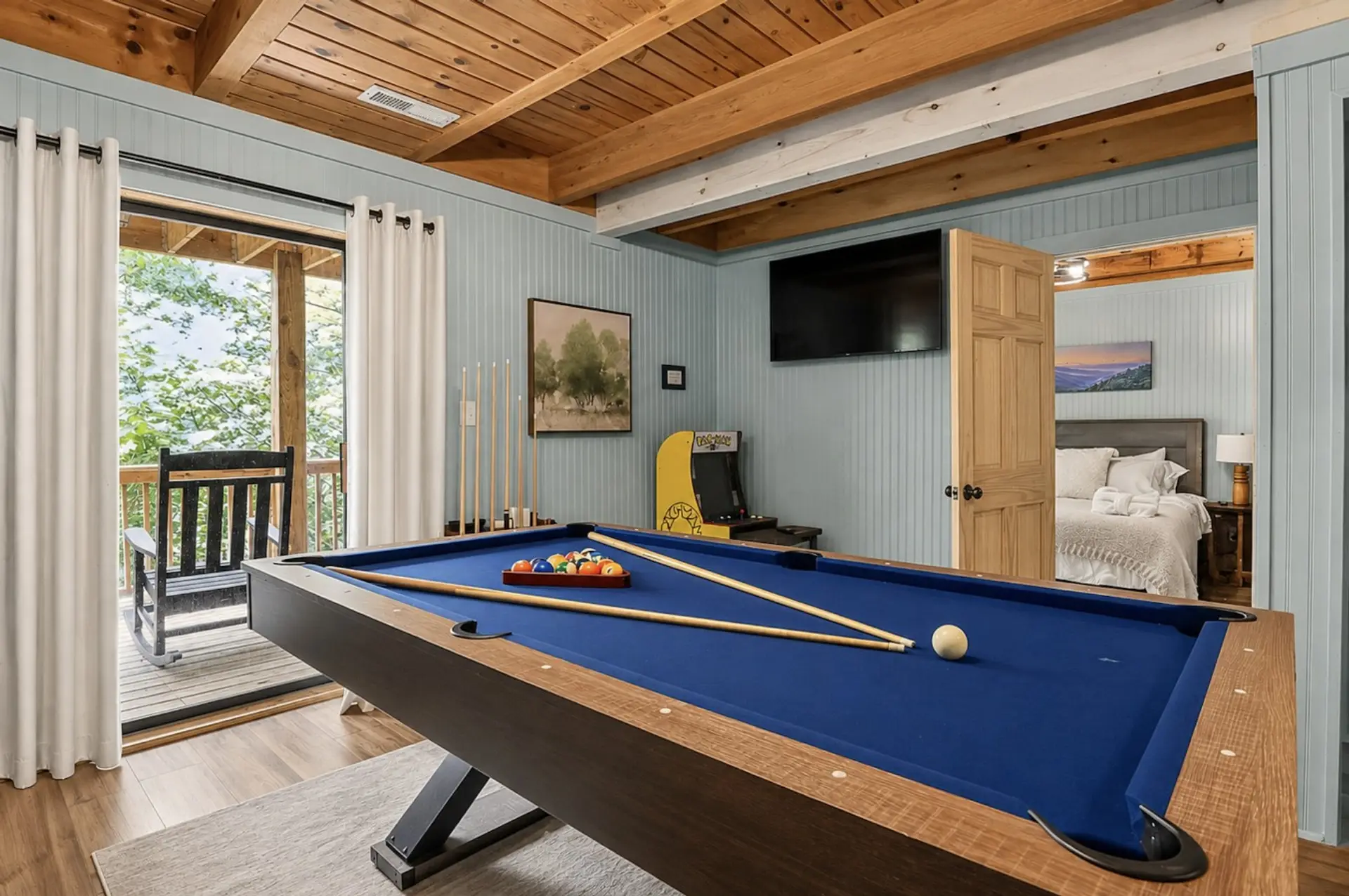 Game room features a pool table, arcade games, Smart TV, deck access, and two twin beds