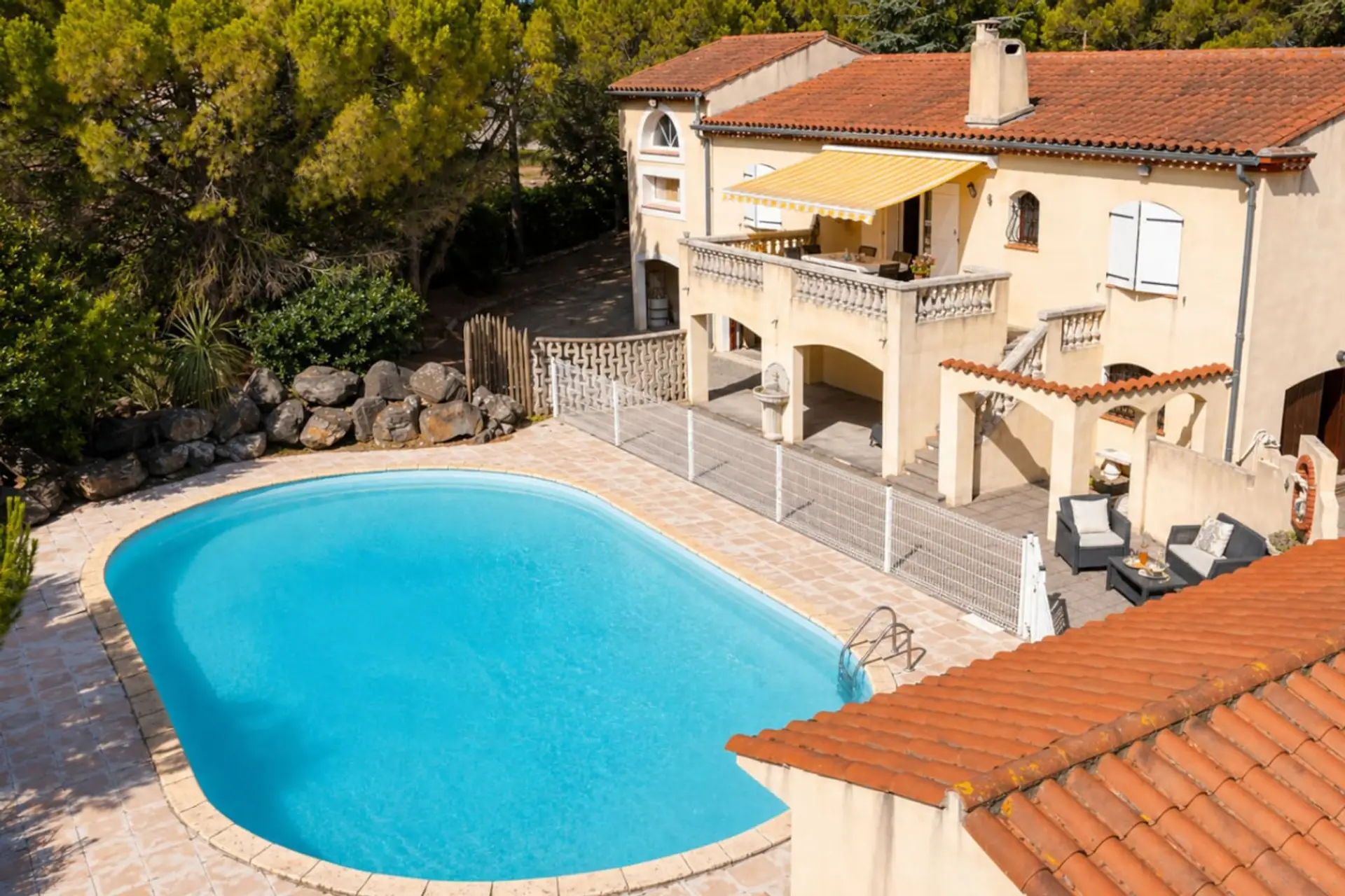 Grande piscine turquoise avec plage carrelée et balustrade attenante à la villa : espace sécurisé pour se détendre et se relaxer après avoir exploré Carcassonne.