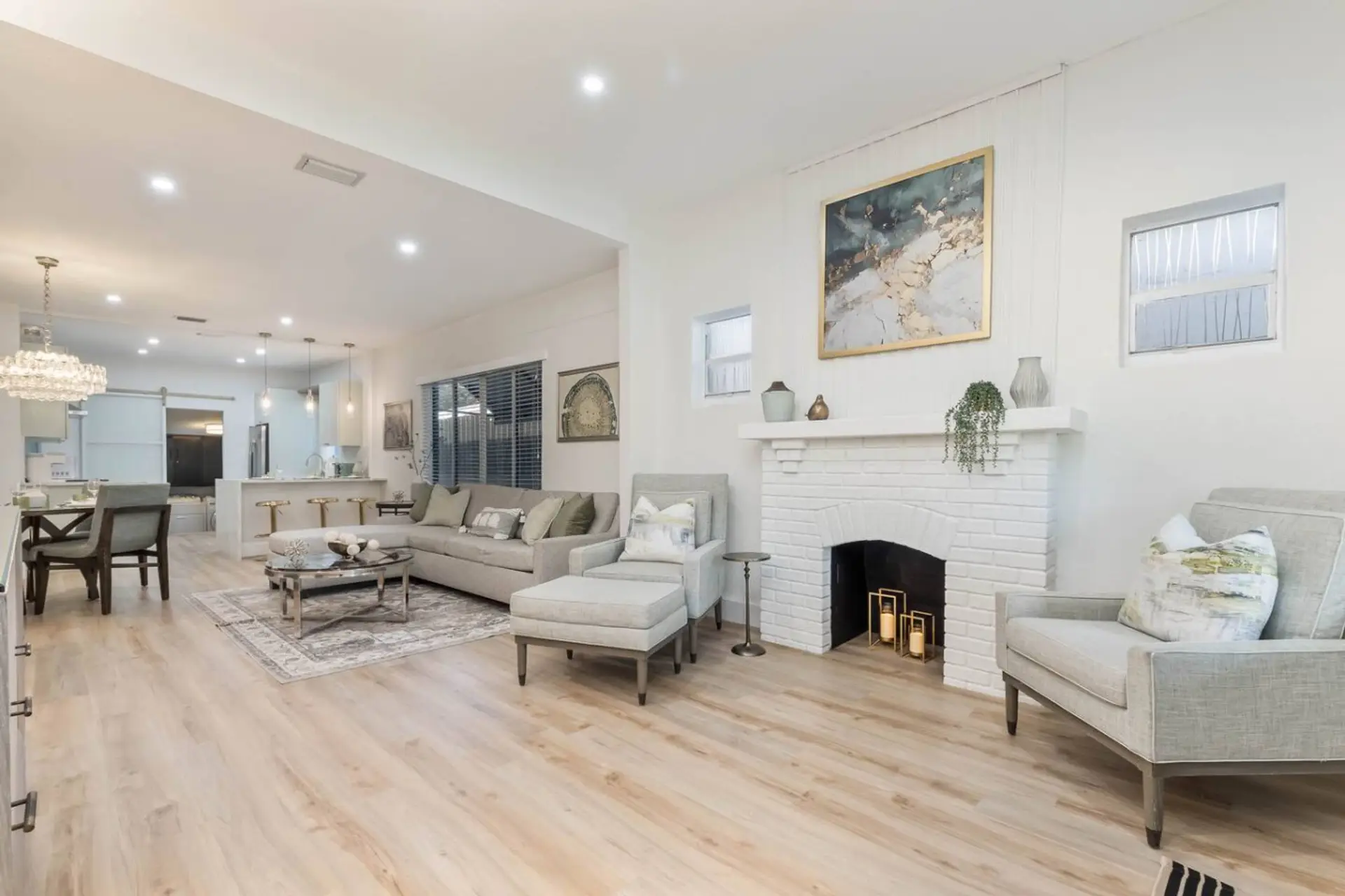Bright living room with decorative white brick fireplace (candles inside, non-working), sectional sofa and light wood floors
