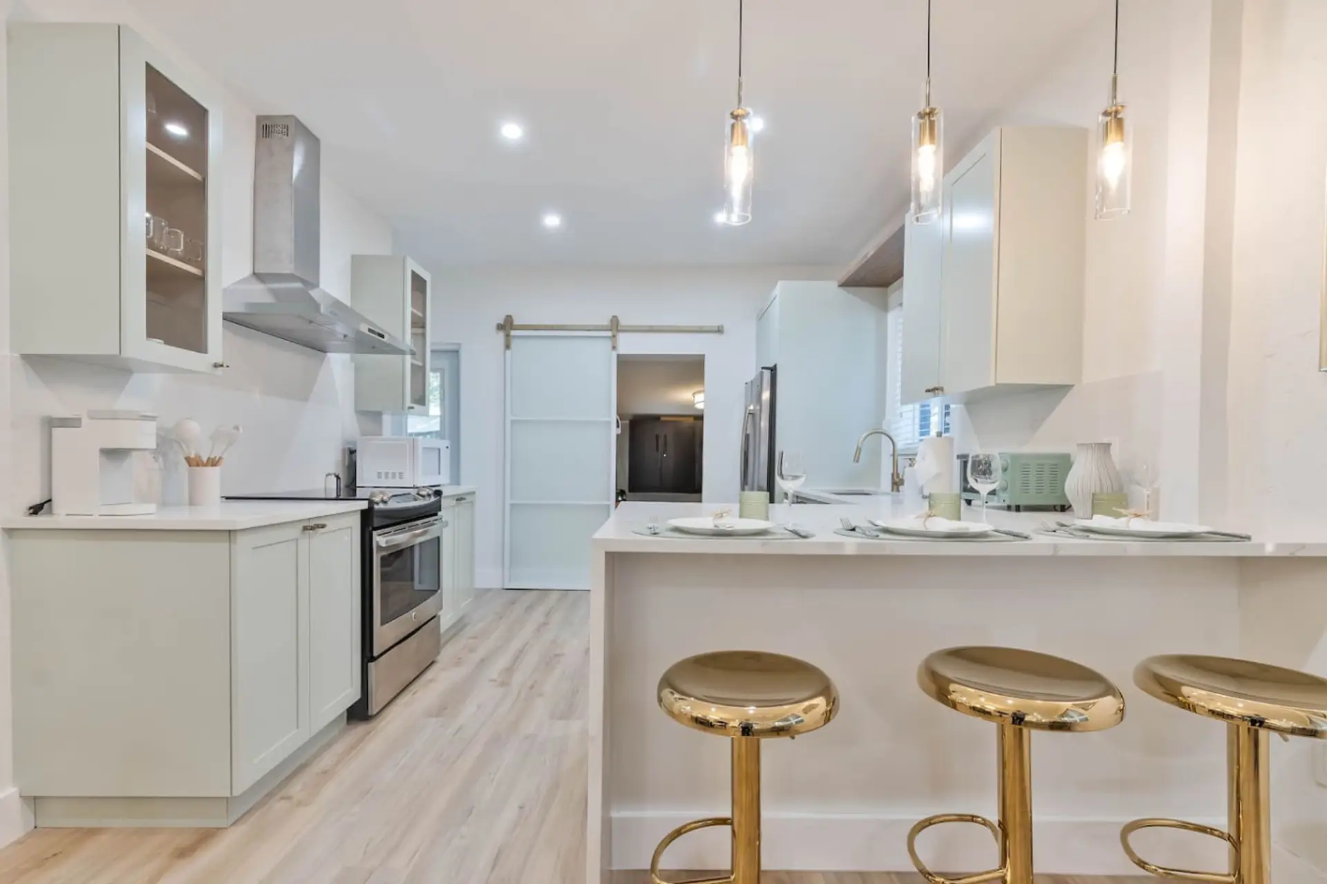 Modern kitchen with white cabinets, stainless steel appliances and island with bar stools