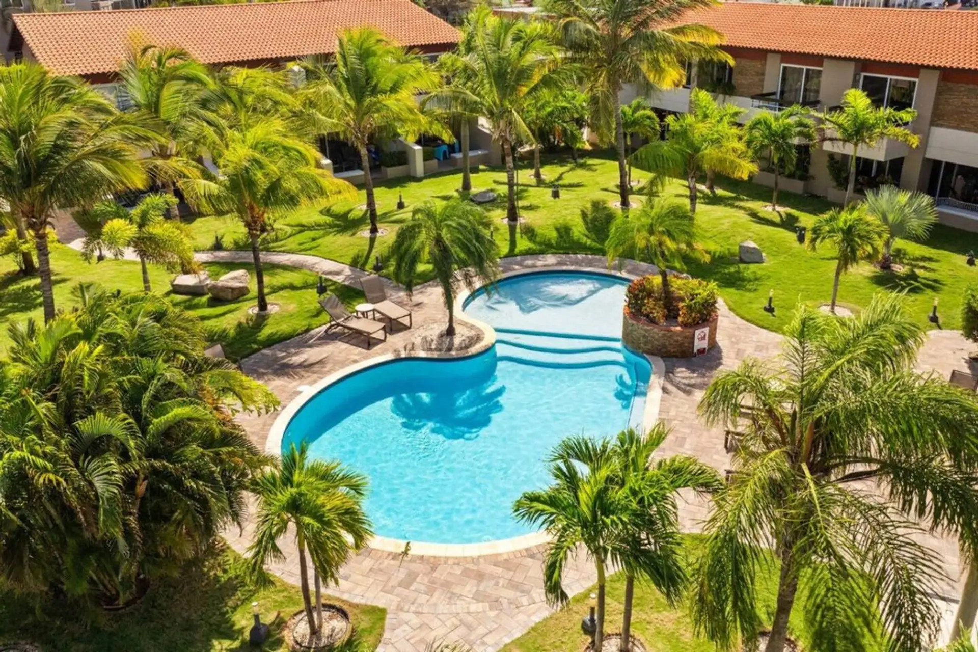 Tropical resort-style pool surrounded by lush gardens, perfect for relaxation.