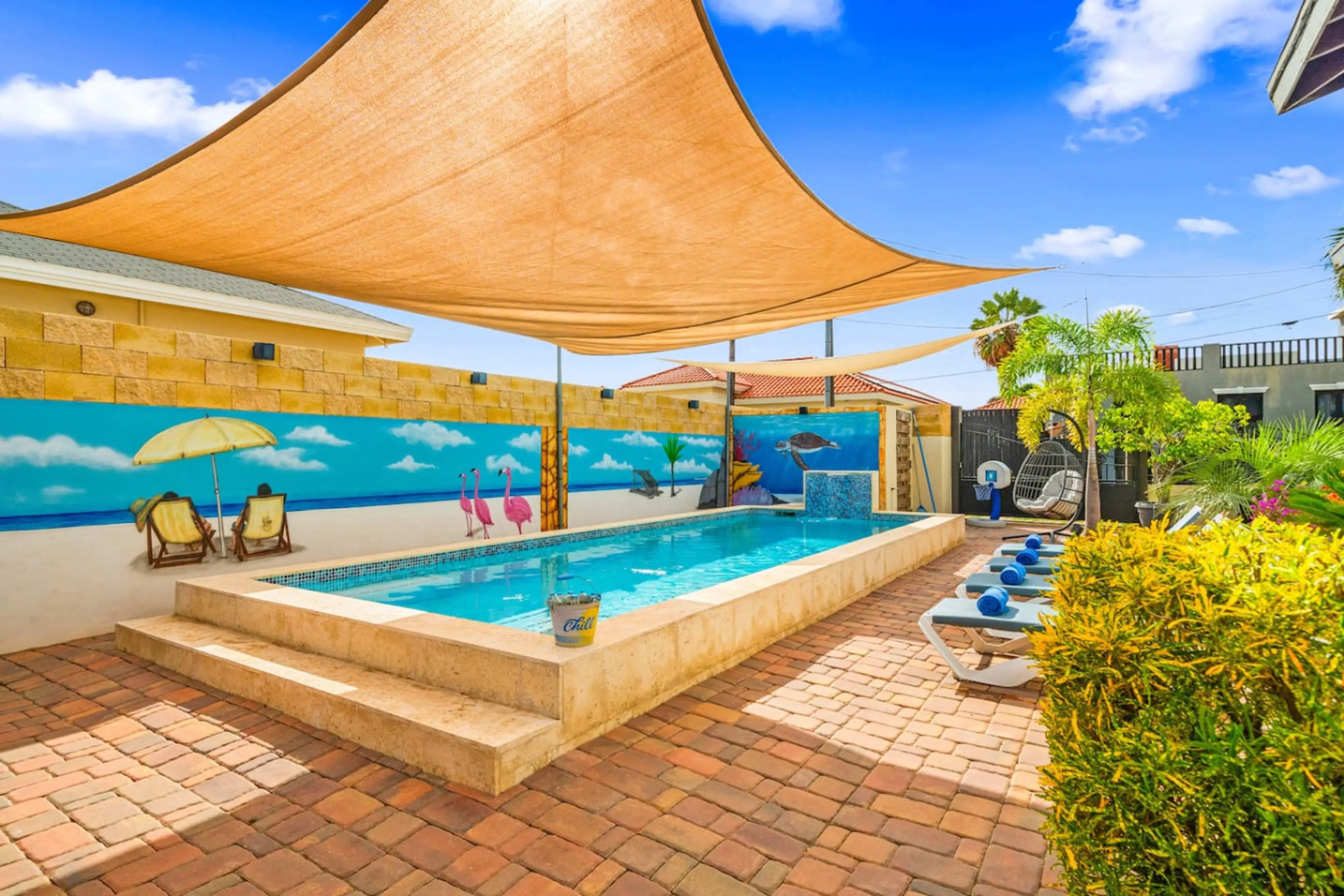 Private Aruba villa pool with shaded areas and tropical mural backdrop