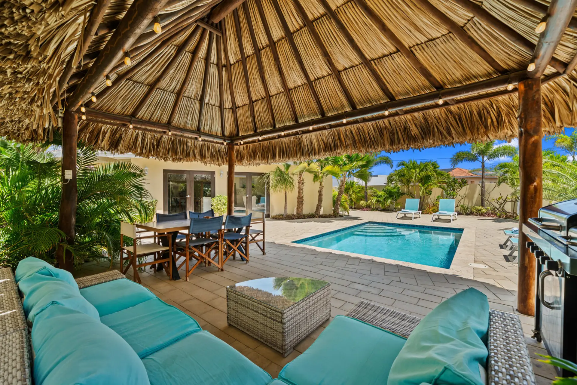 Shaded palapa lounge and dining area beside private pool for relaxed Aruba living
