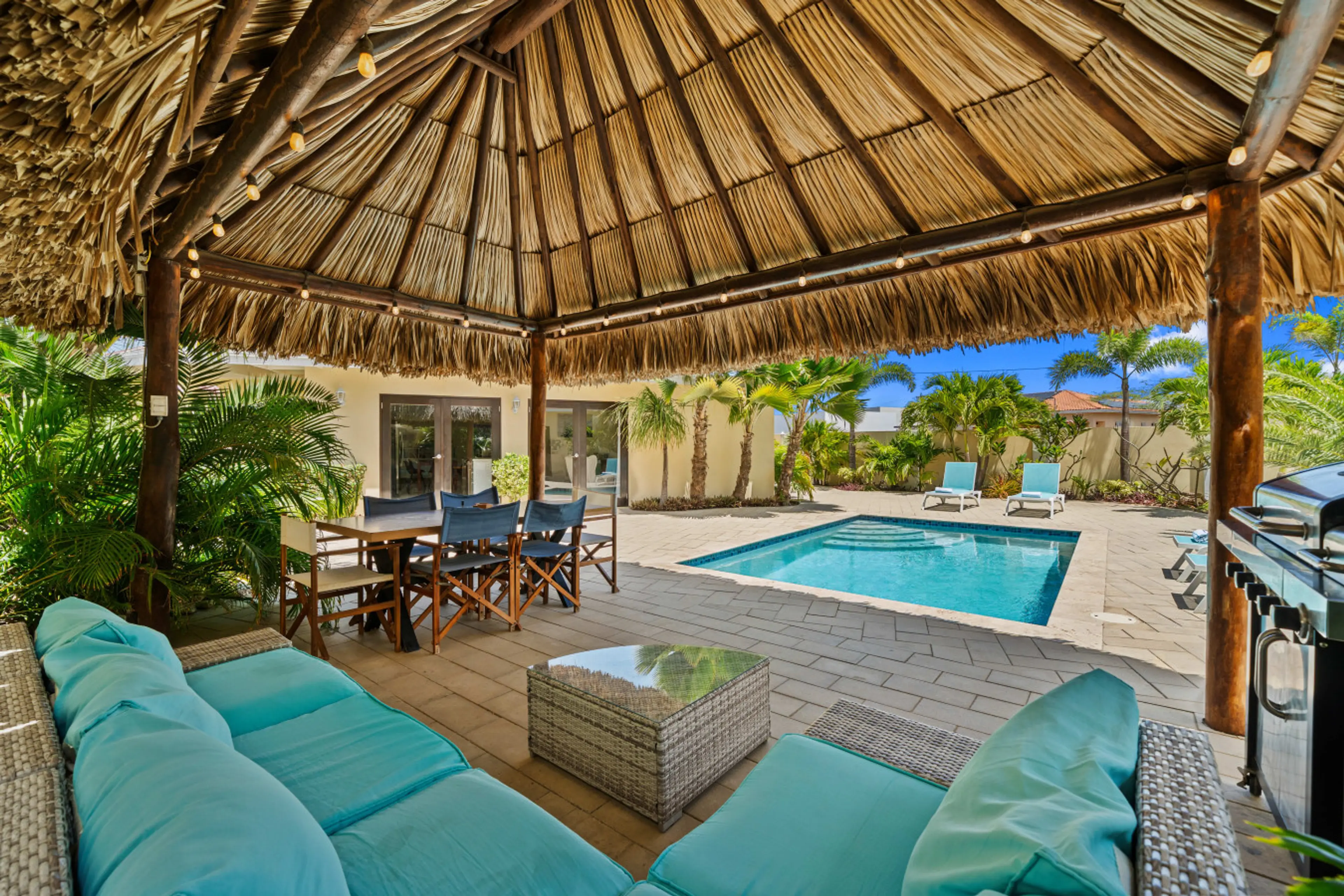 Shaded palapa lounge and dining area beside private pool for relaxed Aruba living