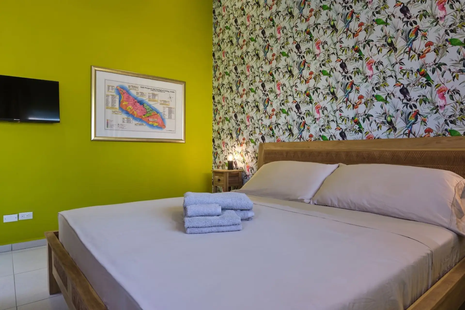 This bright bedroom pairs plush bedding with vibrant tropical walls, creating a cheerful retreat where you can recharge in comfort after a sun-filled day in Aruba.