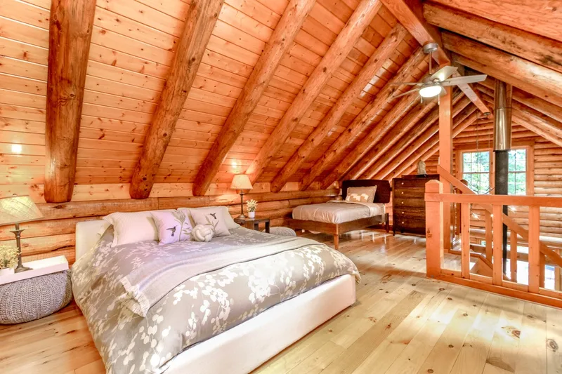 Airy loft bedroom with two beds beneath wood beams
