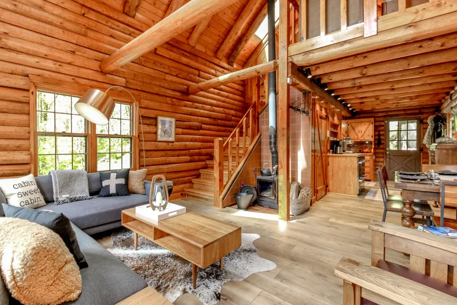 Open log cabin living room with wood stove and loft
