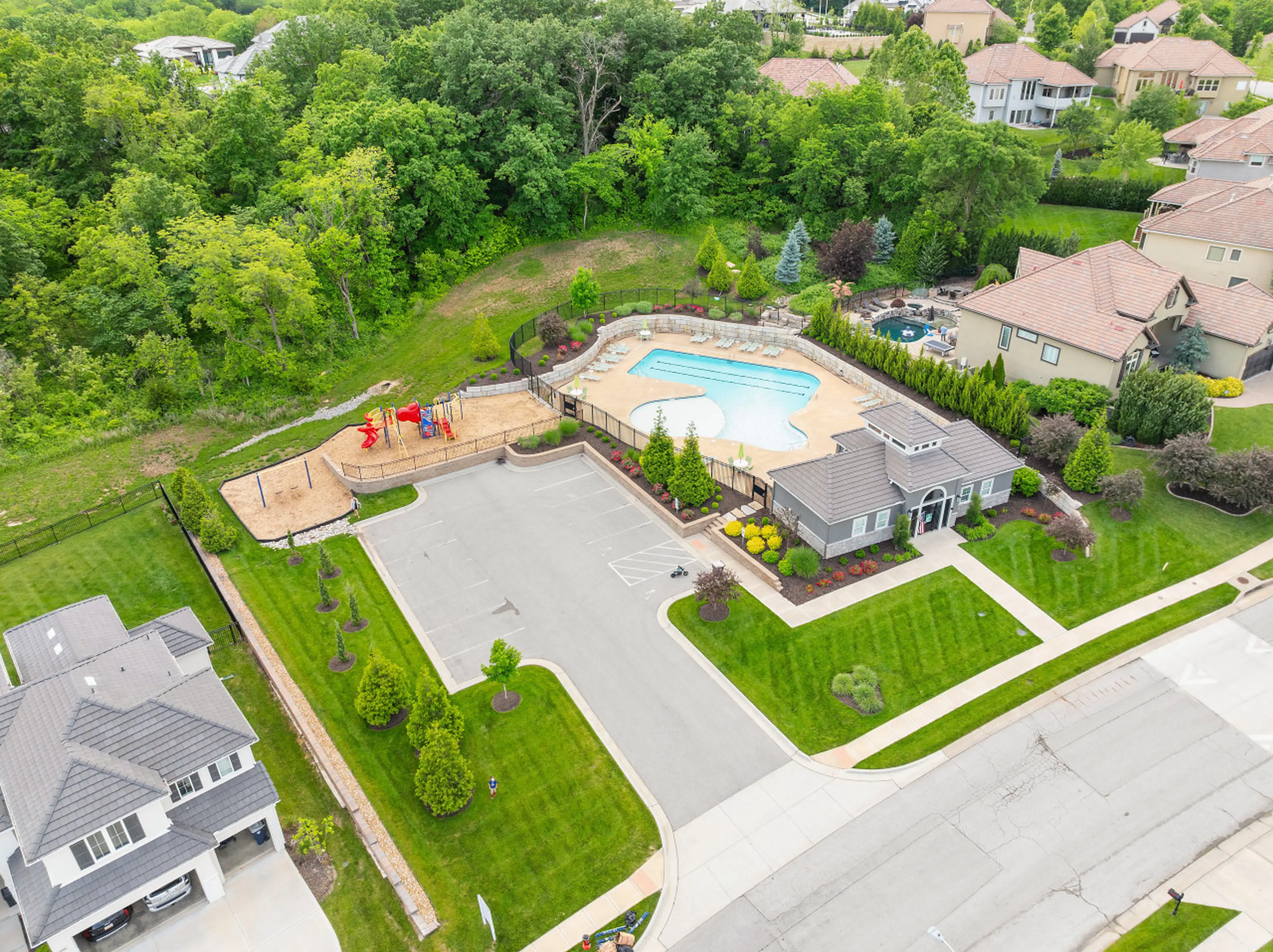 Discover the heart of this vibrant community, captured from above. This inviting aerial view showcases a sparkling swimming pool, perfect for summer days, alongside a lively playground where children's laughter fills the air.