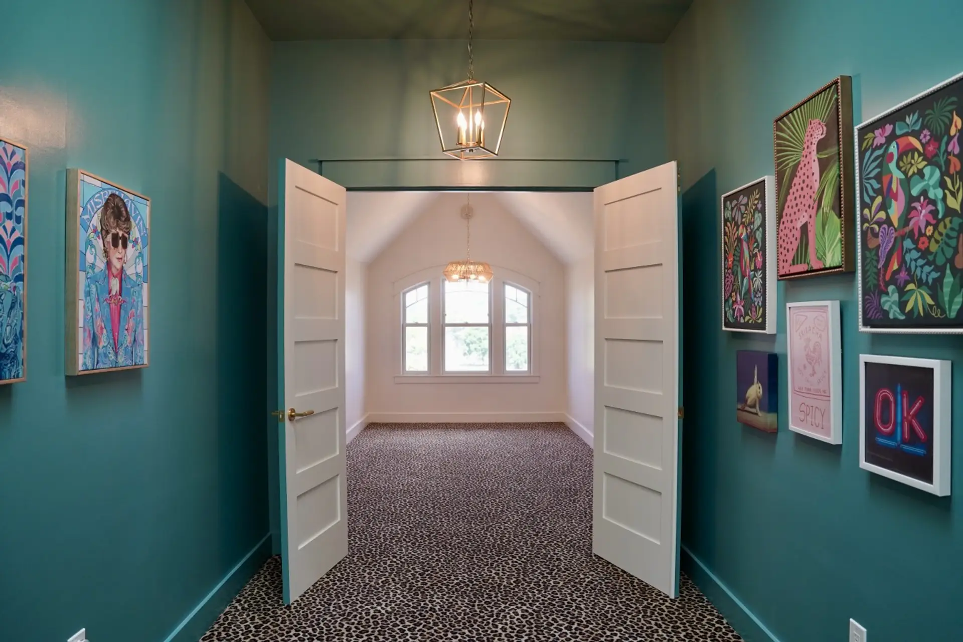 Leopard print carpet and bold gallery walls lead into a bright, vaulted room. A striking mix of pattern and color brings unexpected personality to this space, making the walk into the room part of the experience at Parkway House Goshen.