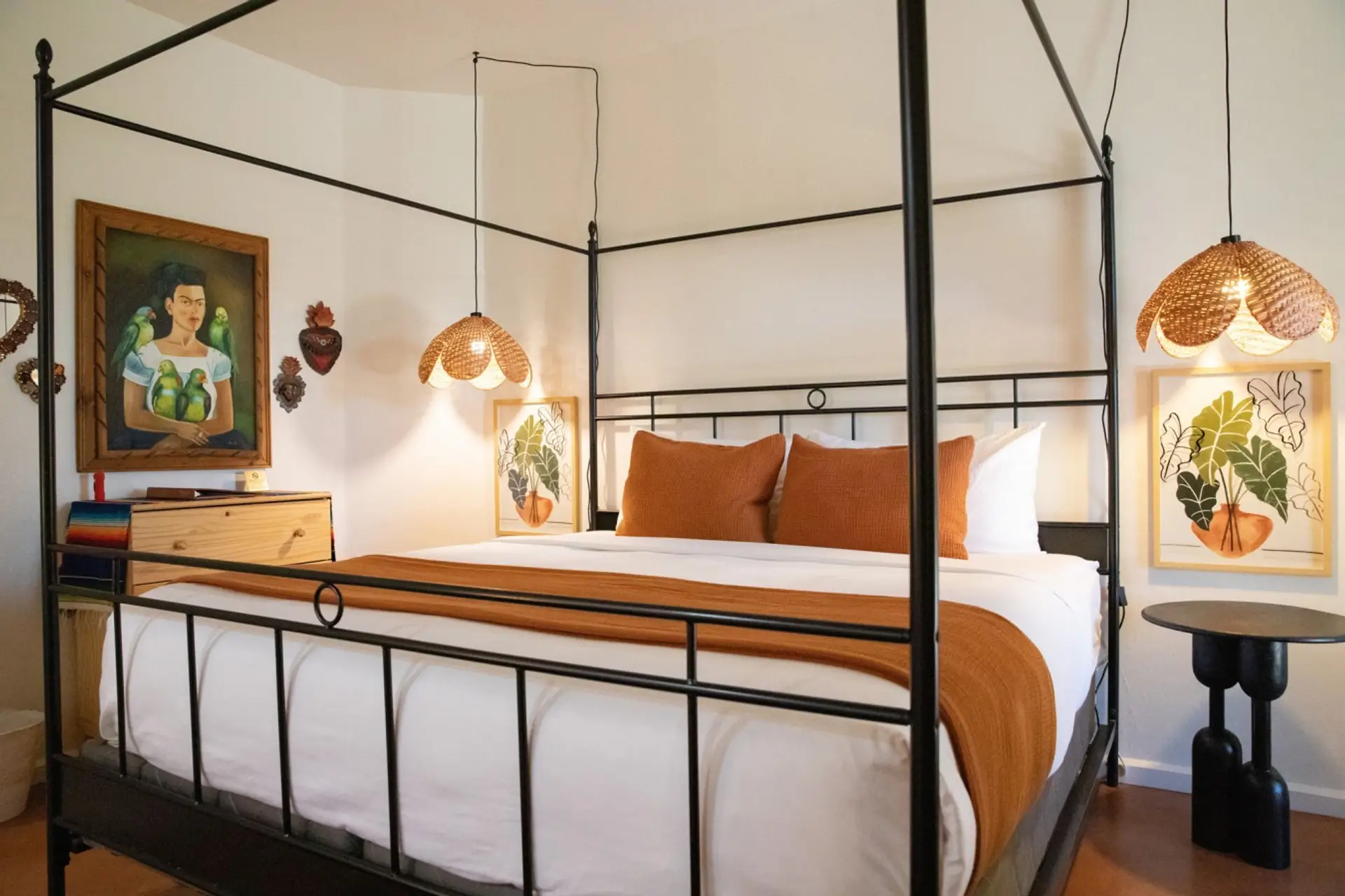 King canopy bed beside a portrait of Frida Kahlo