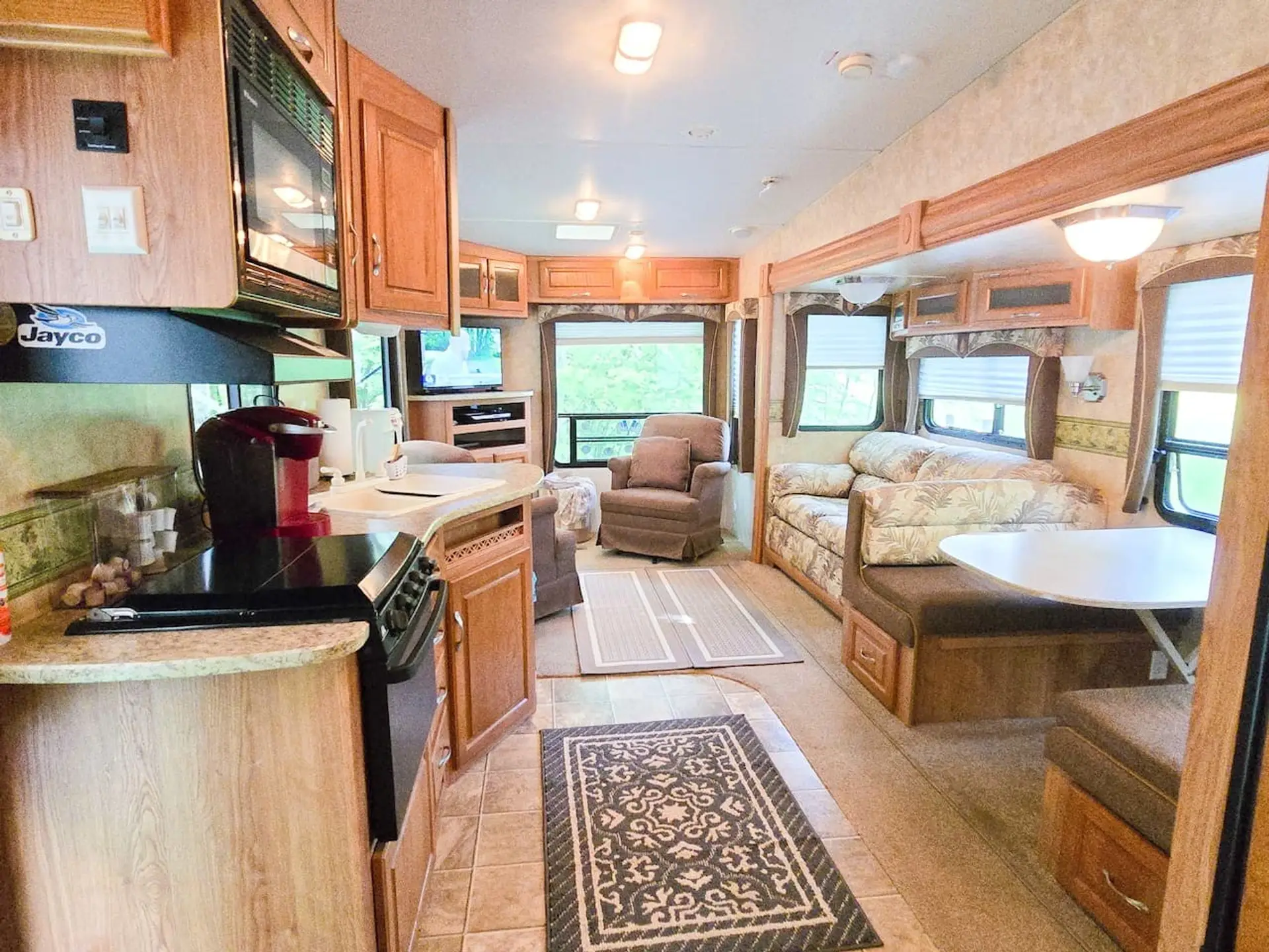 Enjoy the comforts of home inside our cozy camper, complete with a kitchen, dining nook, comfortable seating, and TV.
