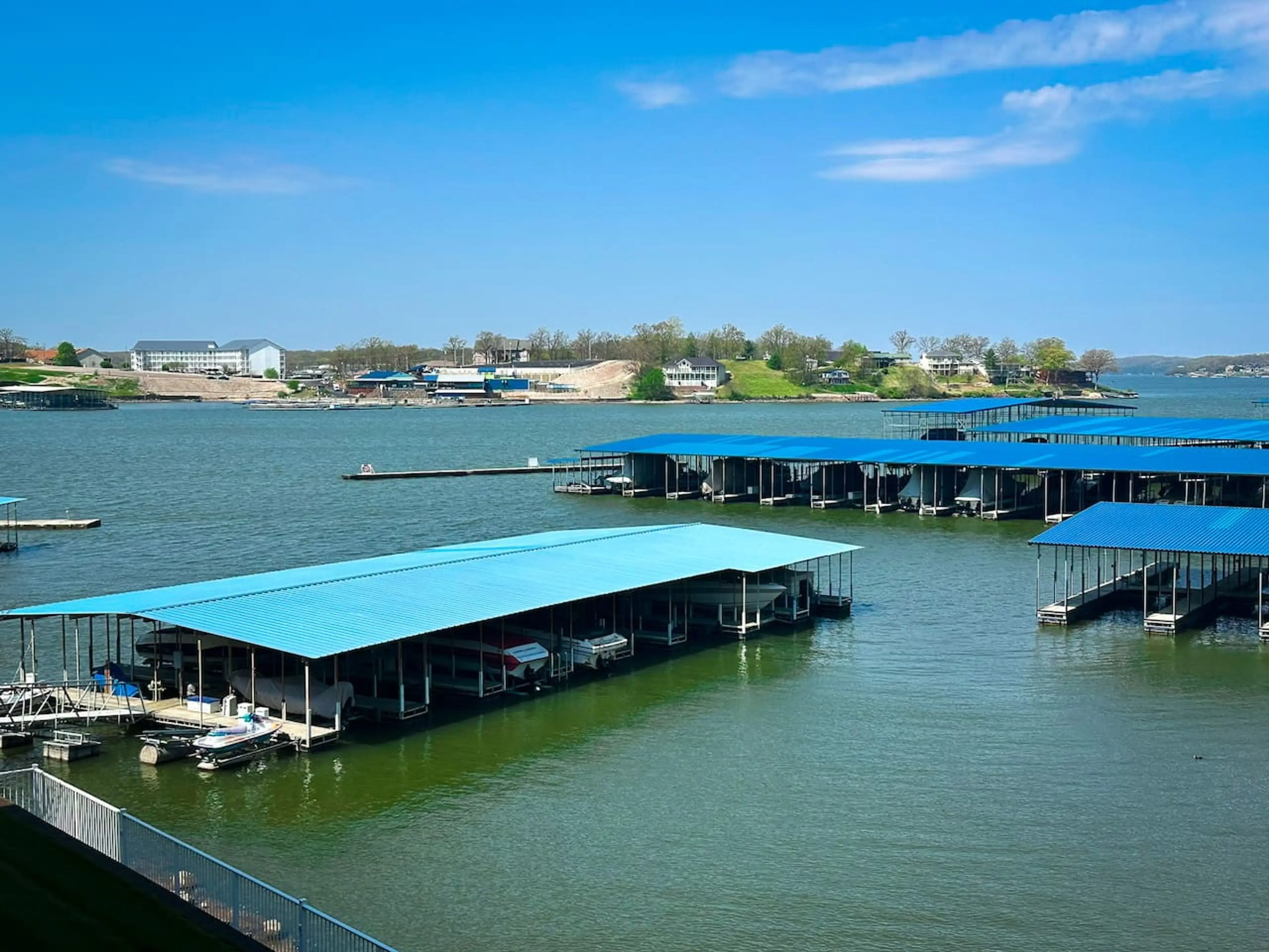 This vibrant lakeside community offers stunning views of the water, with multiple covered boat docks providing convenient access for water activities. The serene landscape, dotted with charming lakeside residences, promises a relaxing and picturesque