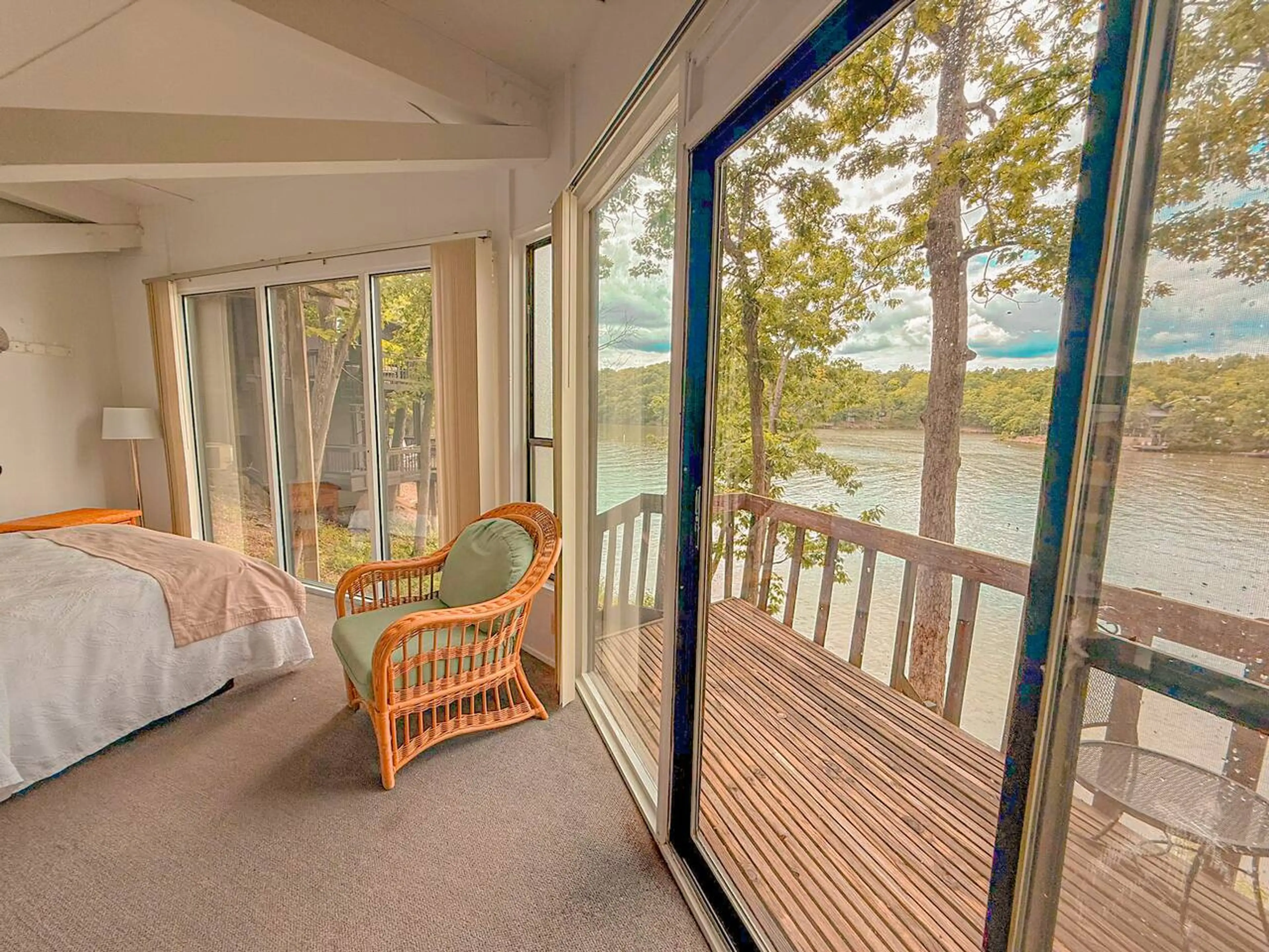 Wake up to the serene beauty of the lake from this inviting bedroom, featuring large windows and direct access to the deck.