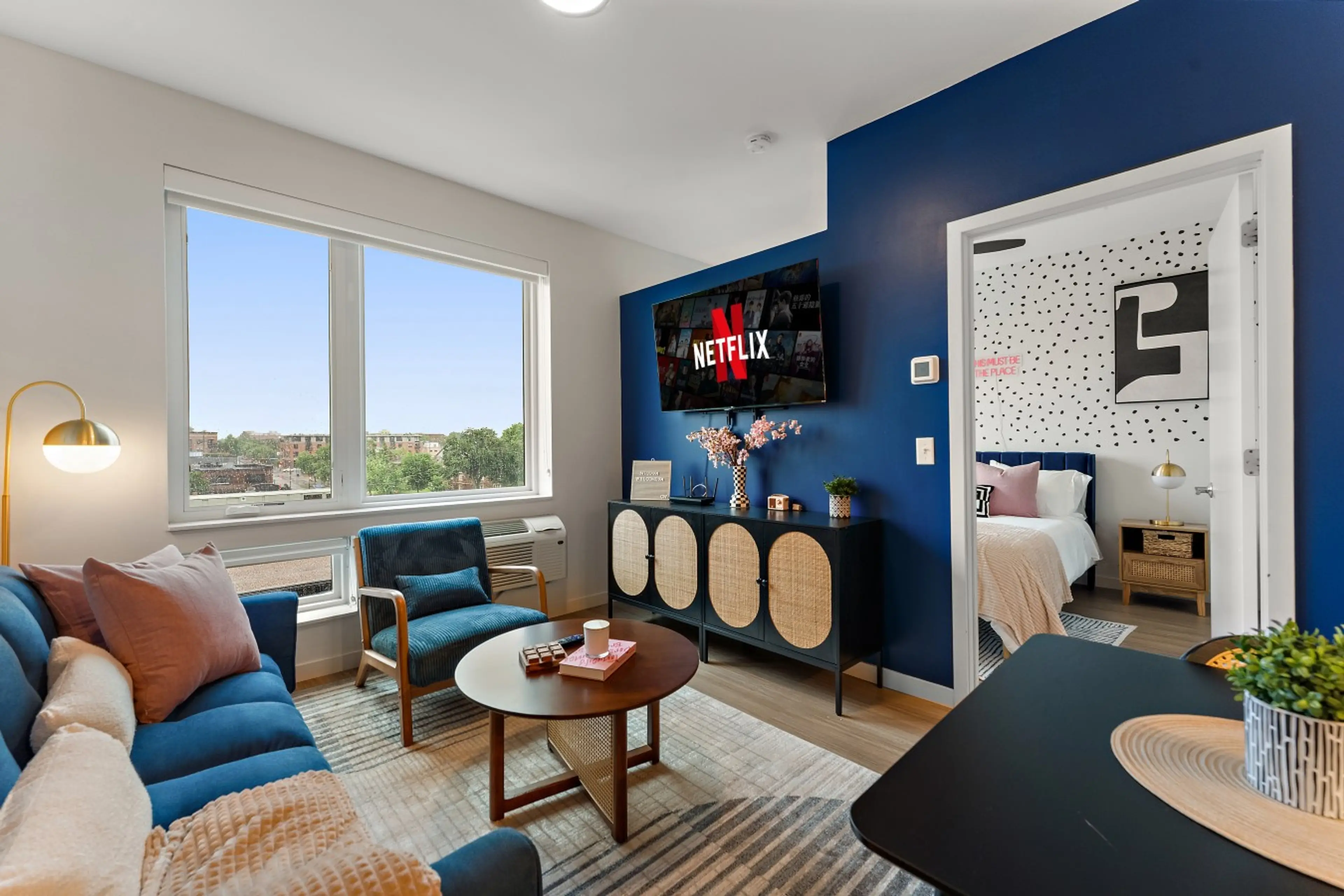 Bright and stylish living area with skyline views, cozy seating, smart TV, and modern décor.