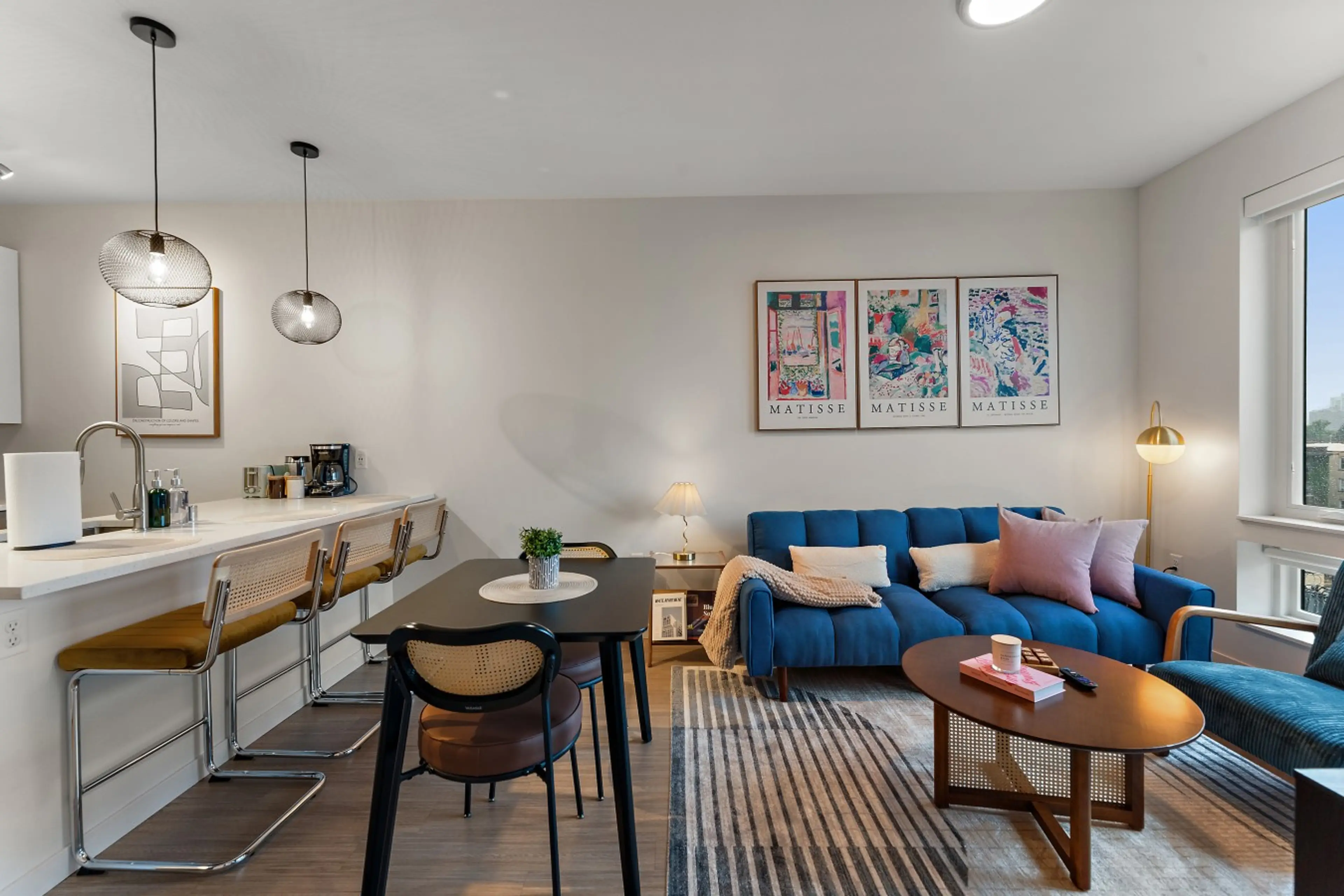 Open-concept living, dining, and kitchen area with comfortable seating, workspace, and natural light