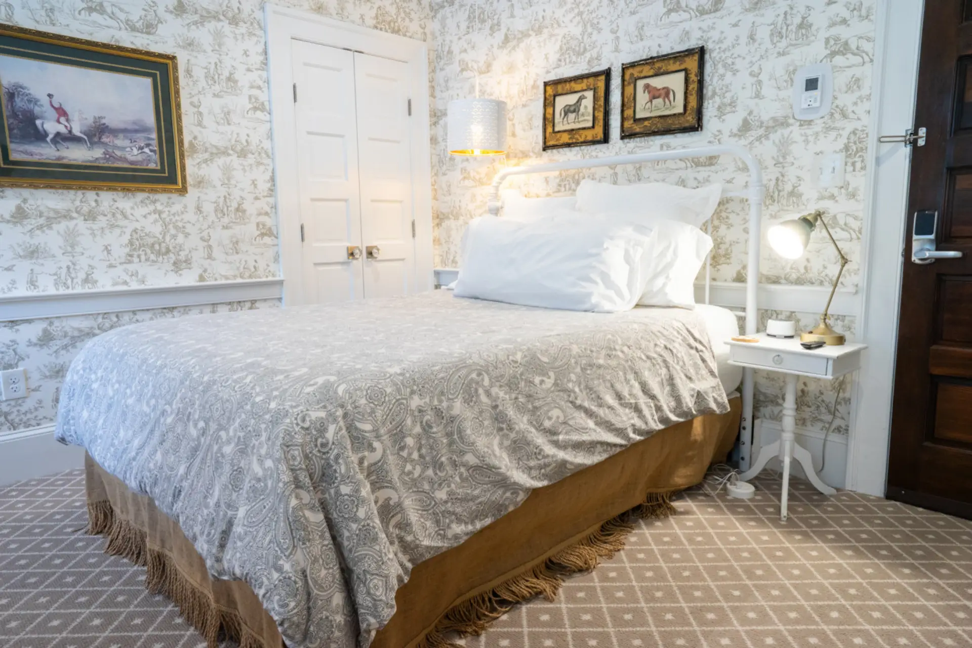 A cozy queen bedroom featuring timeless equine toile wallpaper and warm neutral tones.