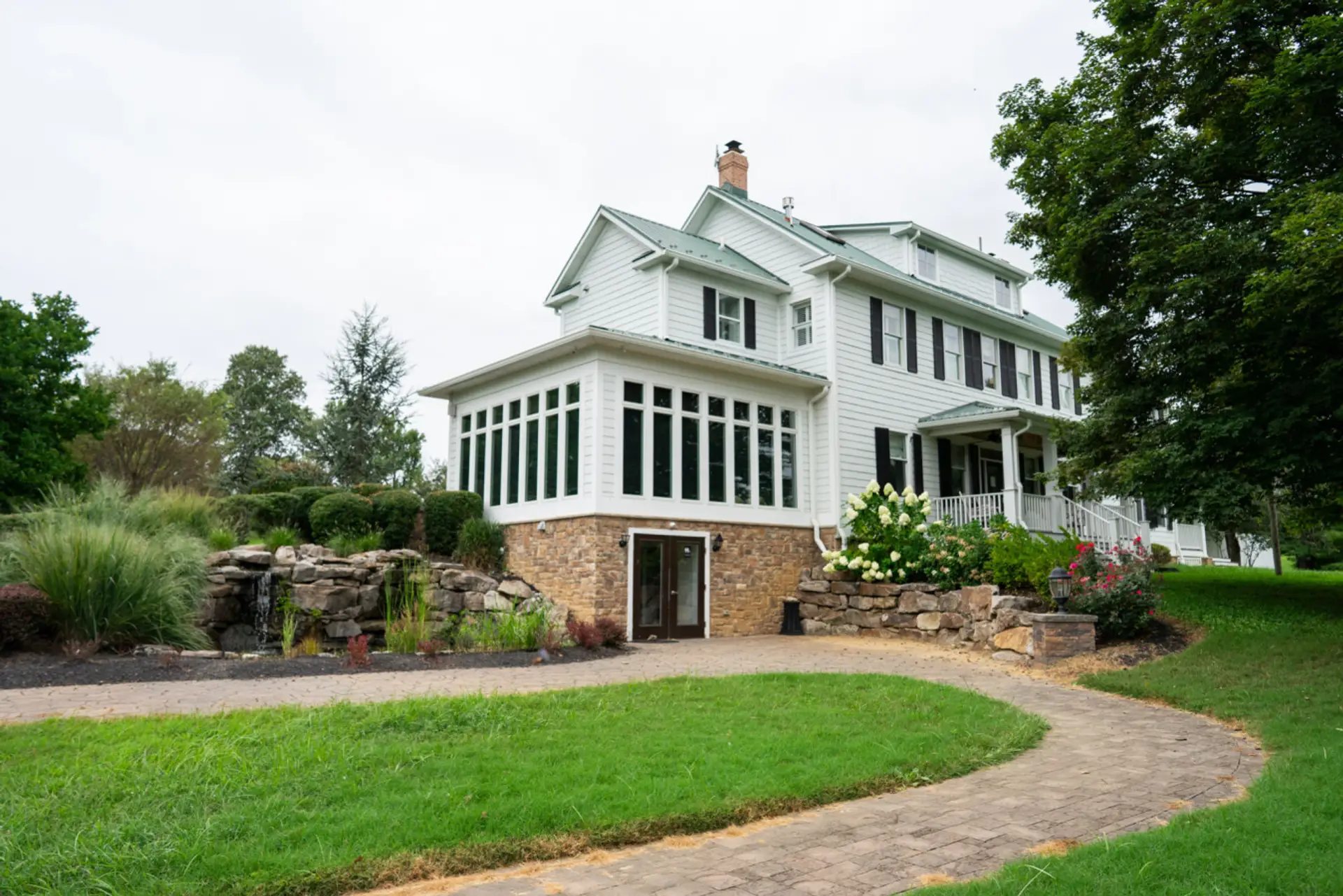 A picturesque view of the inn surrounded by stonework, gardens, and rolling green lawns.