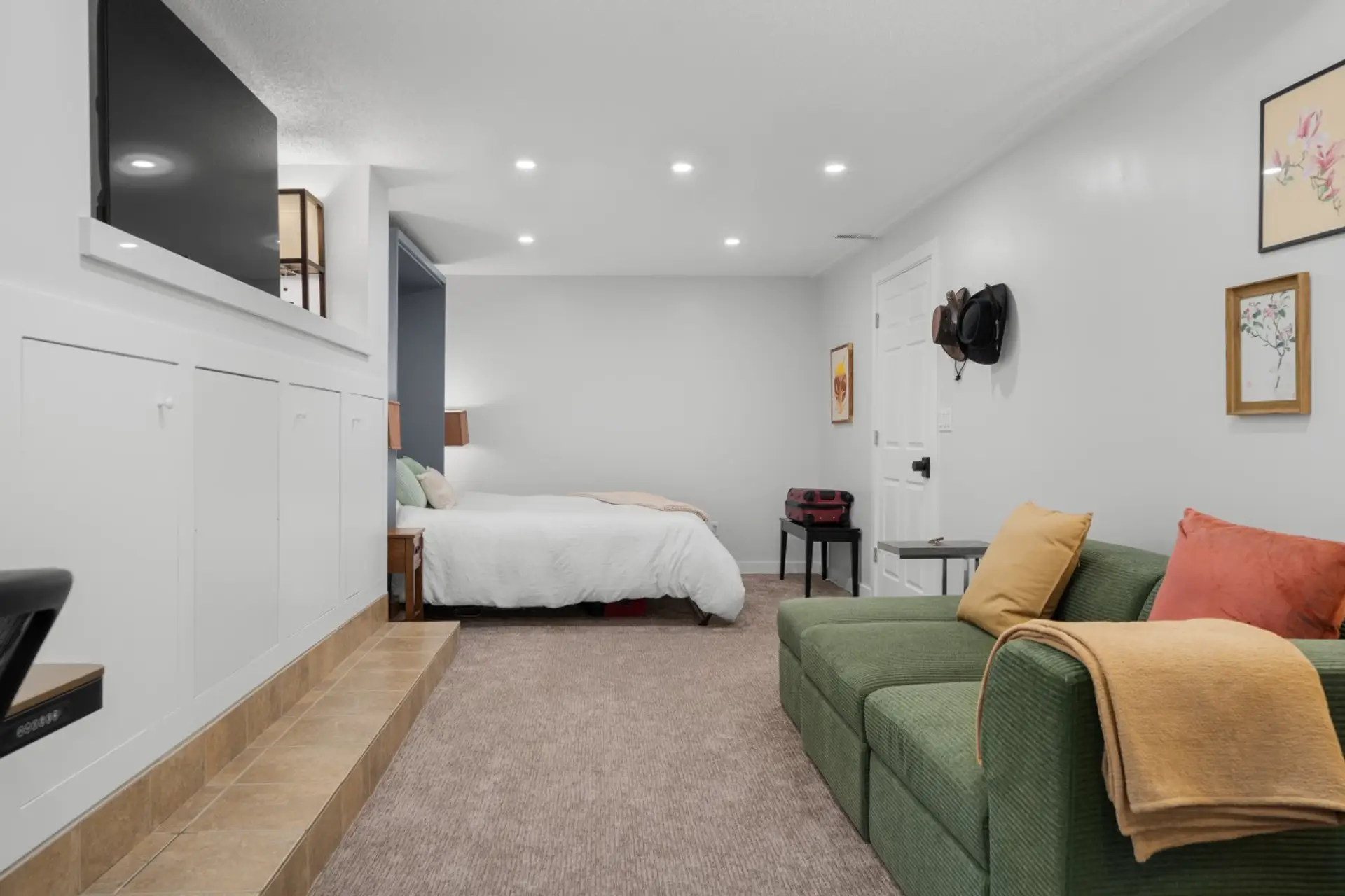 Enjoy this full, private lower-level suite in a modern Marda Loop, Calgary townhouse. The space features a cozy olive-green Cozey sectional, a wall-mounted Smart TV, under-seat storage for luggage, and a comfortable Queen Murphy bed tucked into the backgr