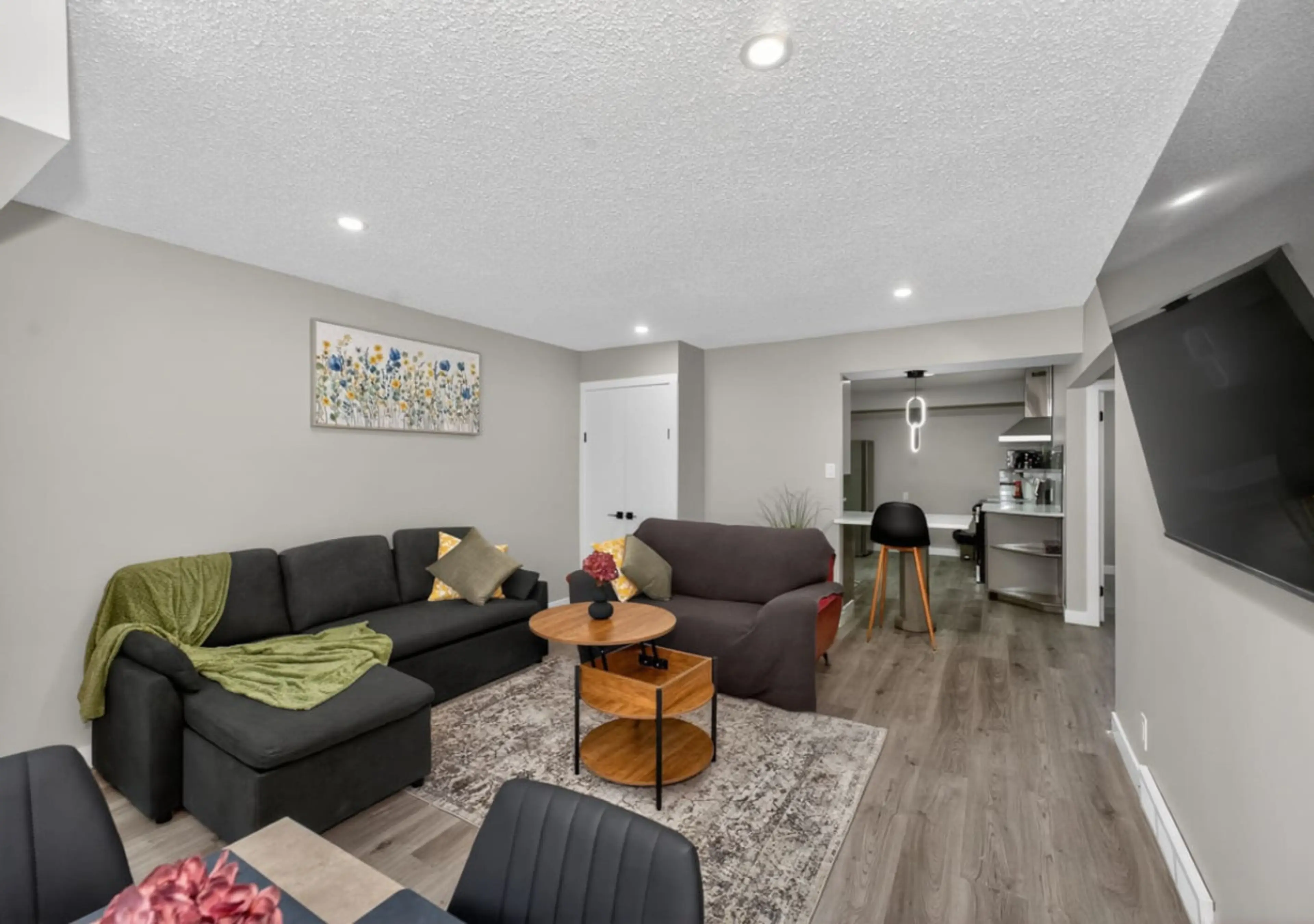 Bright and spacious living area with comfortable sectional sofa and large wall-mounted TV.