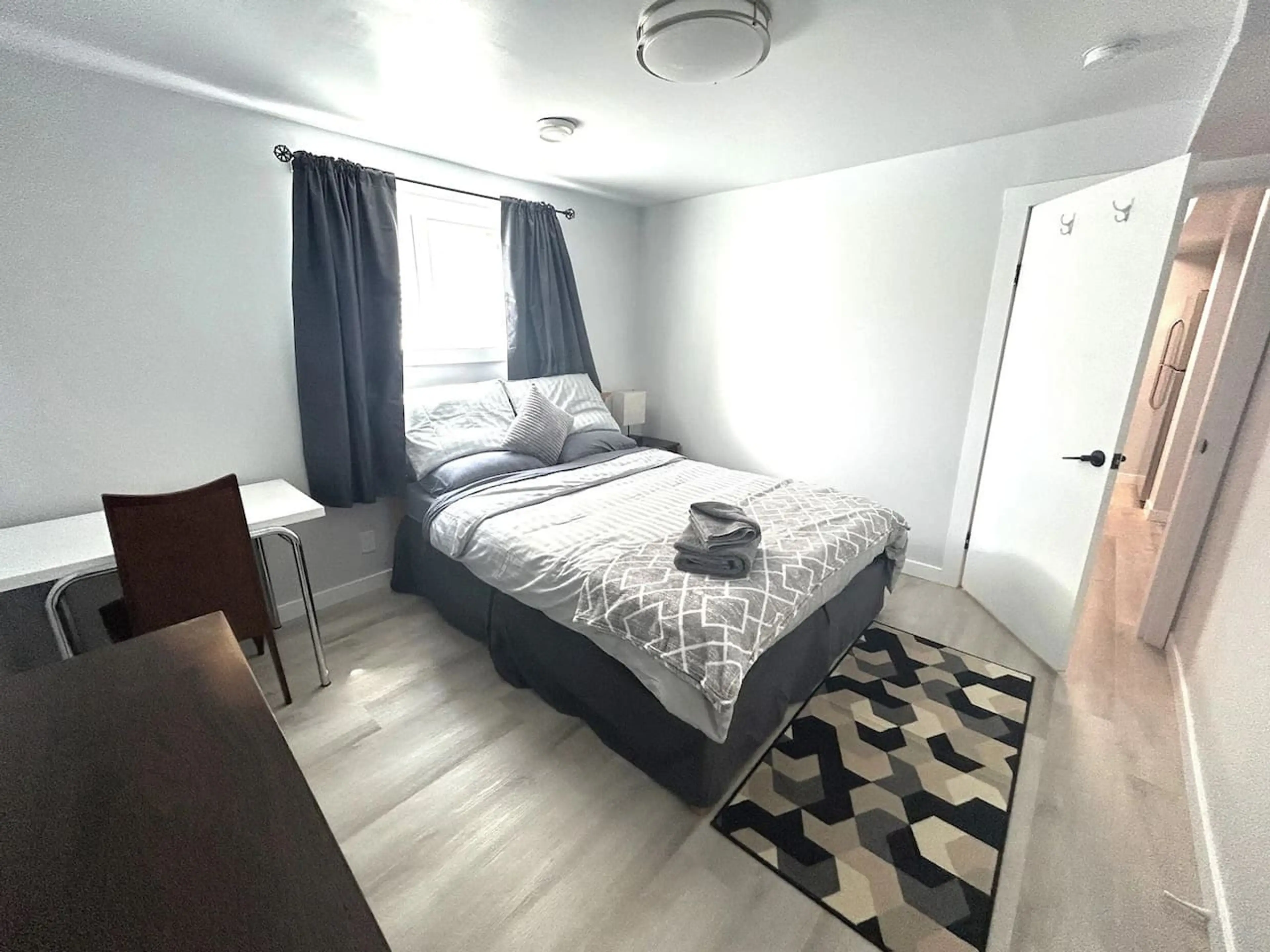 Comfortable queen bedroom with fresh linens, workspace, and natural light