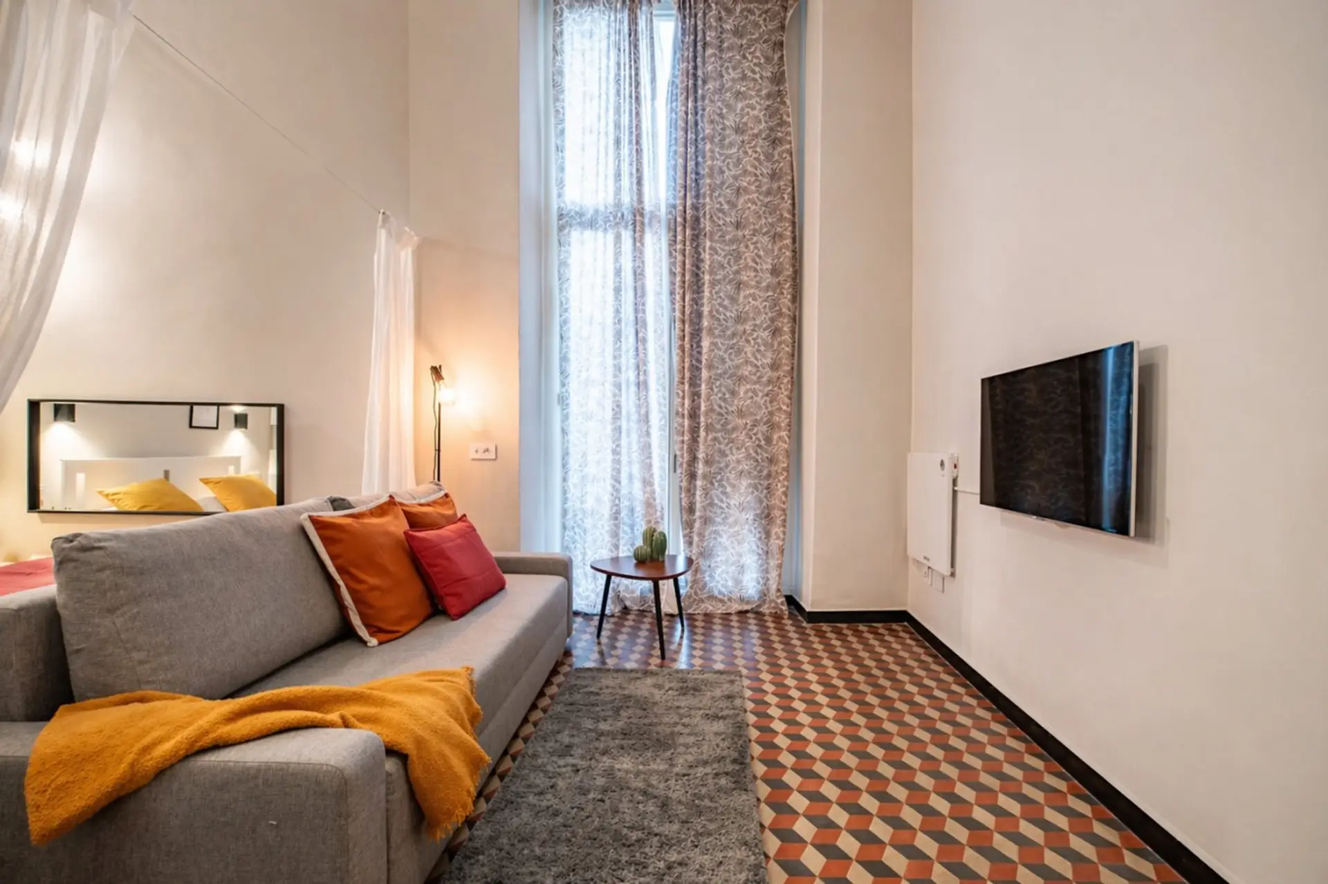 Zona living luminosa con divano comodo, Smart TV e pavimento tipico genovese. Uno spazio rilassante per guardare un film, leggere o riposarsi dopo una giornata alla scoperta dei vicoli del centro storico di Genova.