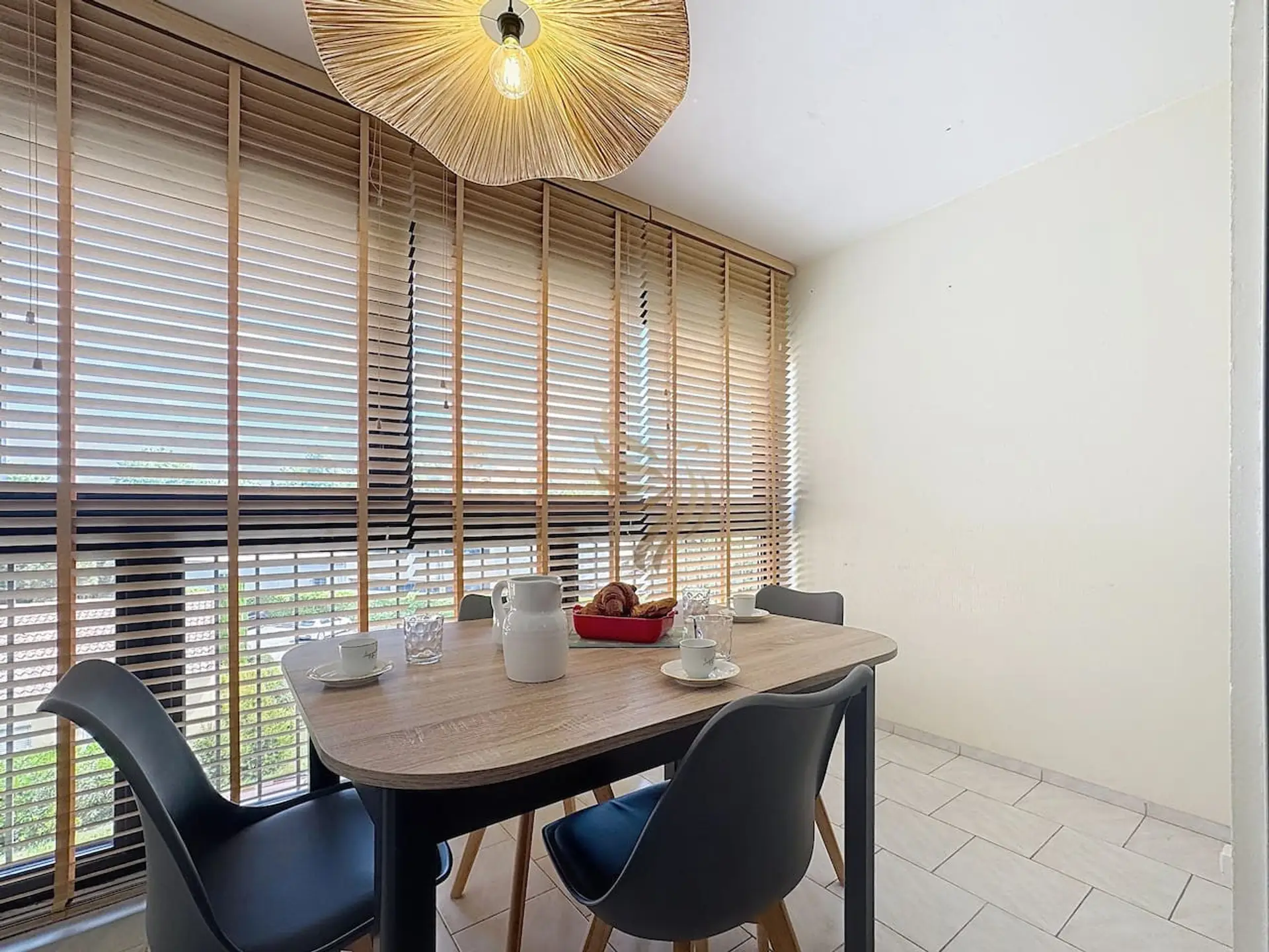 La table en bois clair accentue l'atmosphère chaleureuse. Profitez d'une lumière naturelle abondante pour des repas conviviaux autour de la table, idéale pour les petits groupes.
