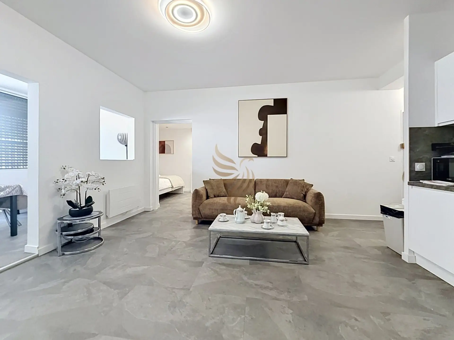 Installez-vous sur le canapé en velours après une journée de visite : une théière sur la table basse en marbre, lumière douce au plafonnier et une décoration épurée créent une pause chaleureuse au cœur de l'appartement.