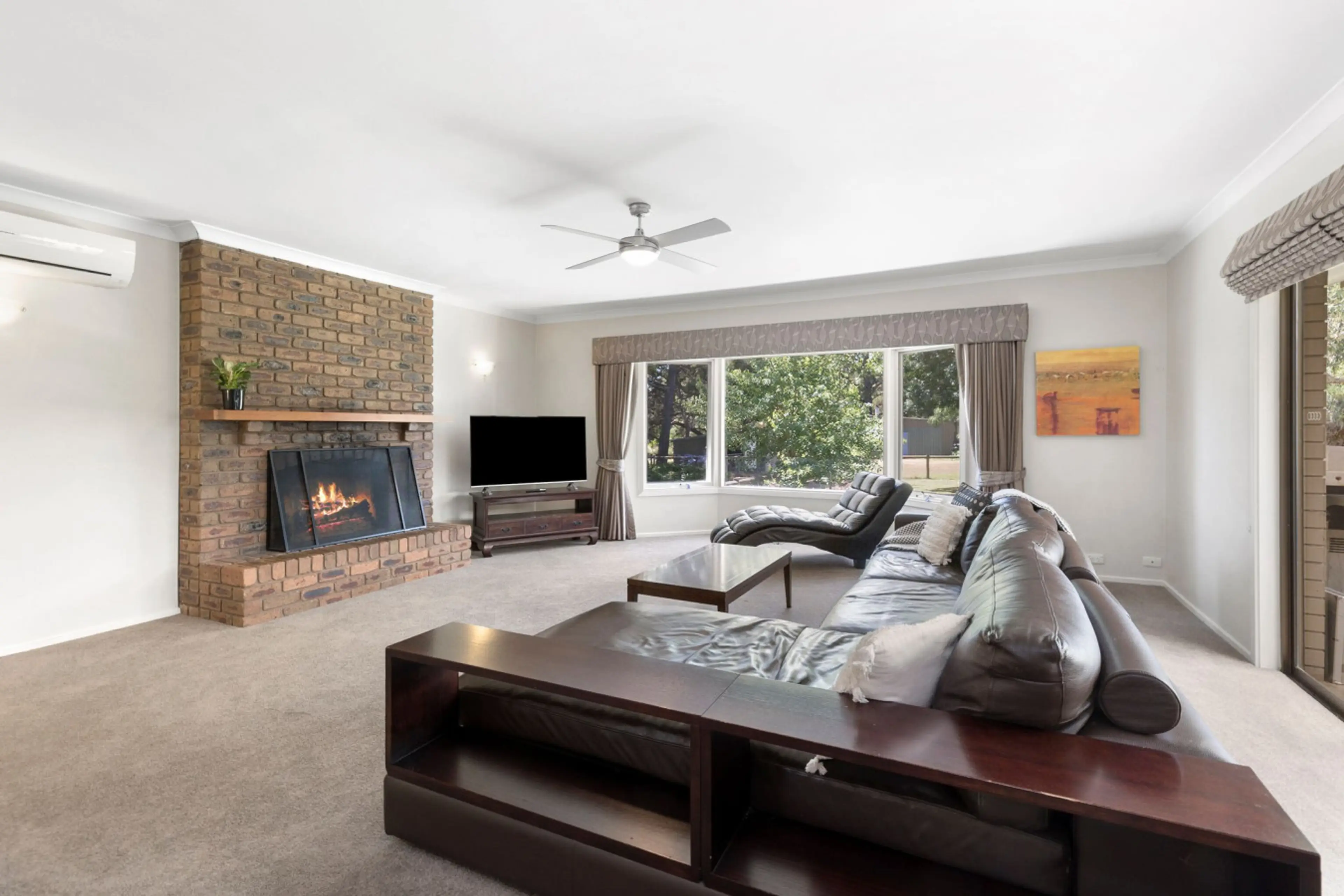 Cosy lounge with brick fireplace, leather sofa, and TV.