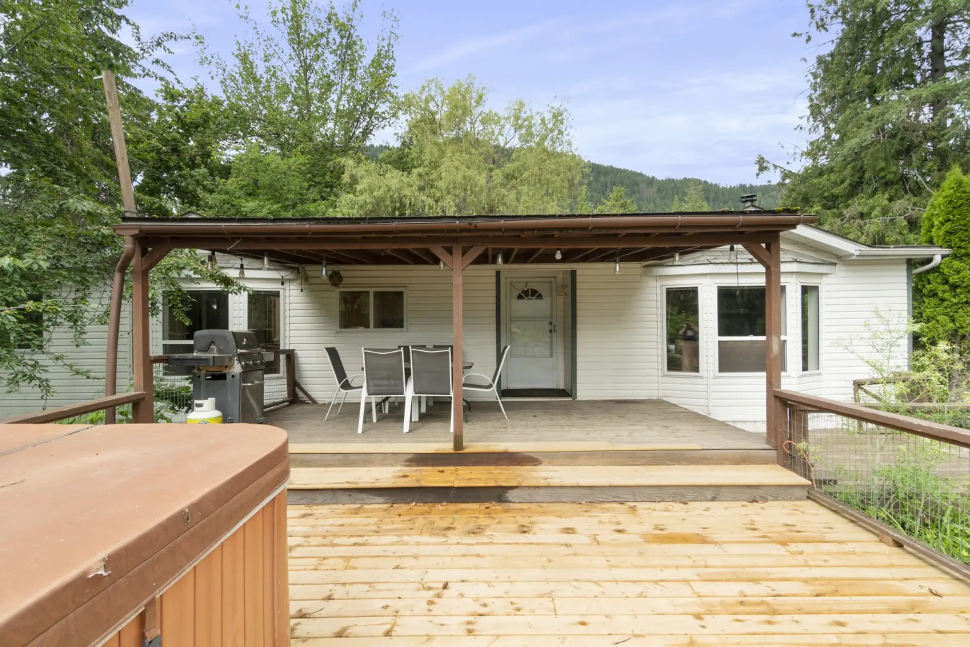 Covered deck with outdoor dining, BBQ, and a private hot tub.