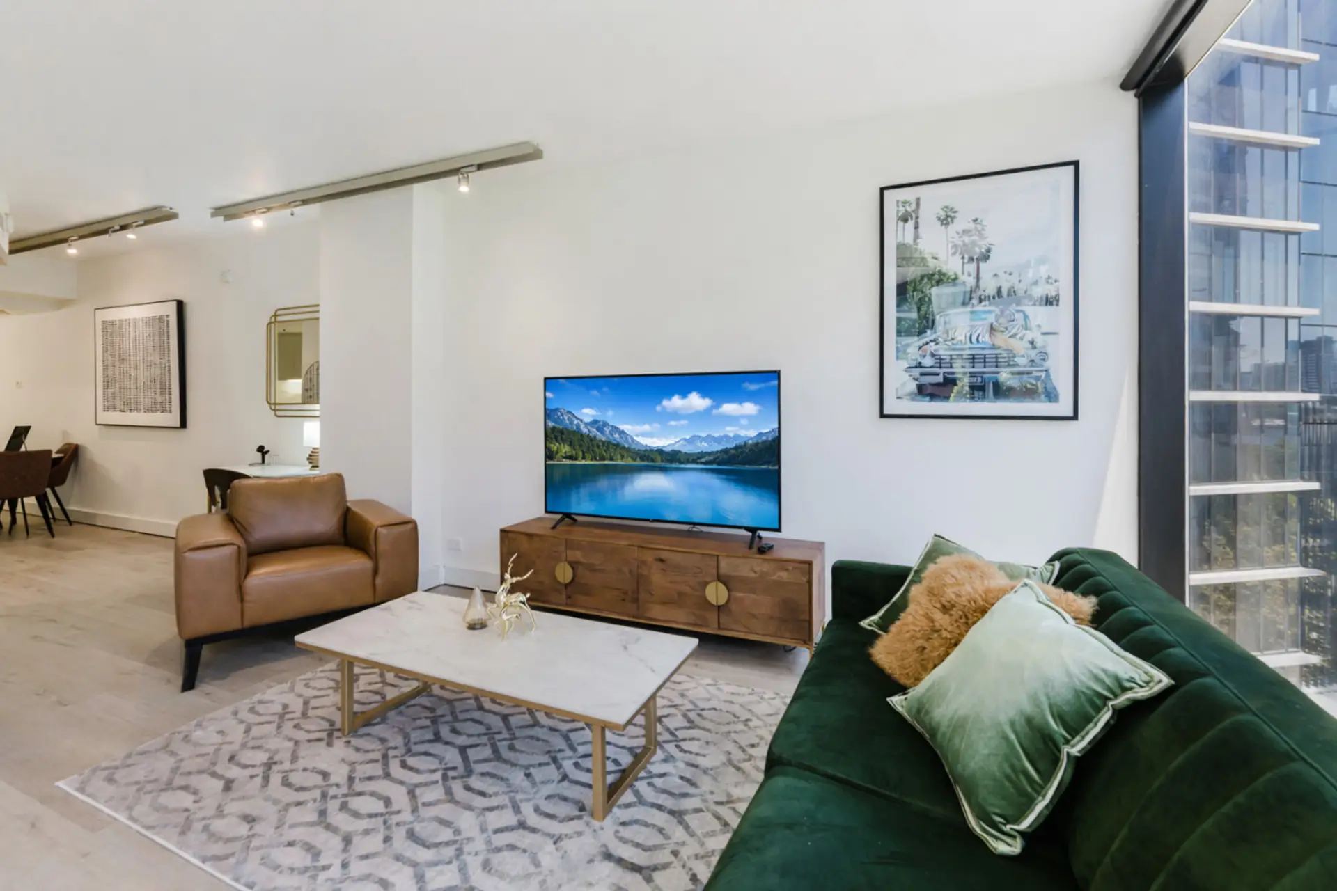 Chic and cozy living area with a blend of modern and classic elements, including a marble-top coffee table, a rich leather armchair, and a striking green velvet sofa.