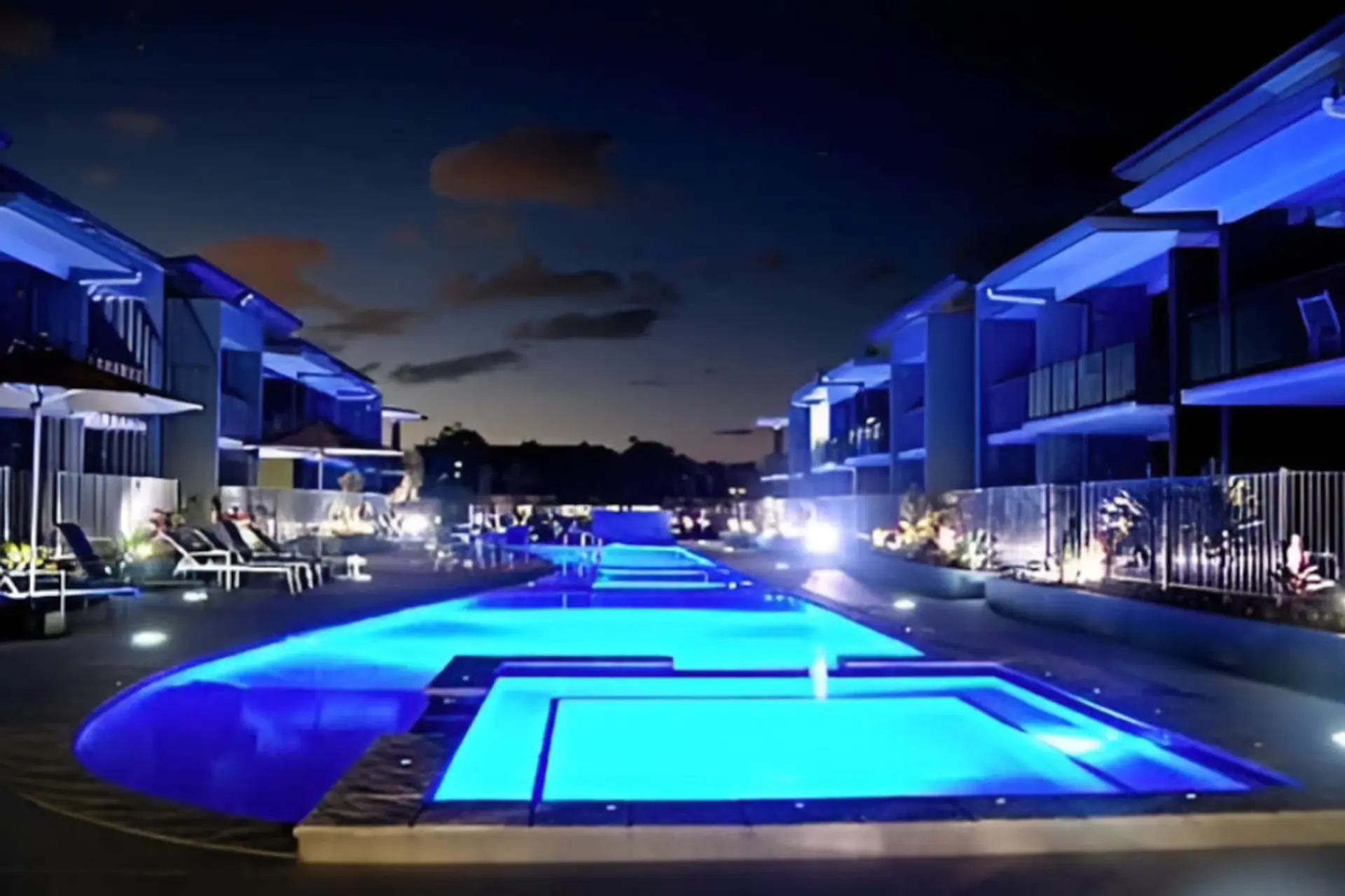Unwind by the illuminated pool under a peaceful night sky
