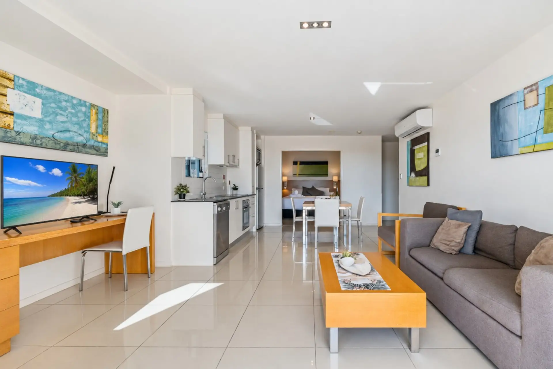 A bright, open-plan living area with a fully equipped kitchen, smart TV, and study desk — comfortable and ready for a longer stay.