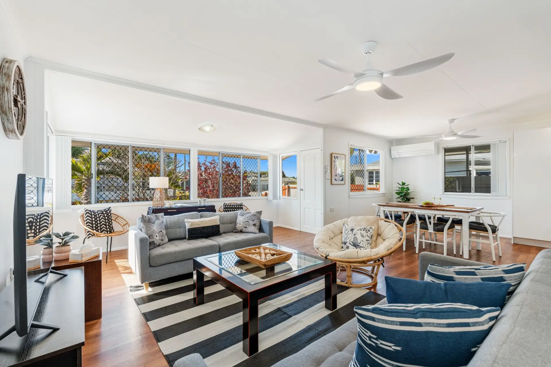 Spacious open-plan living and dining area with timber floors, comfortable lounge, and easy flow through to the kitchen.