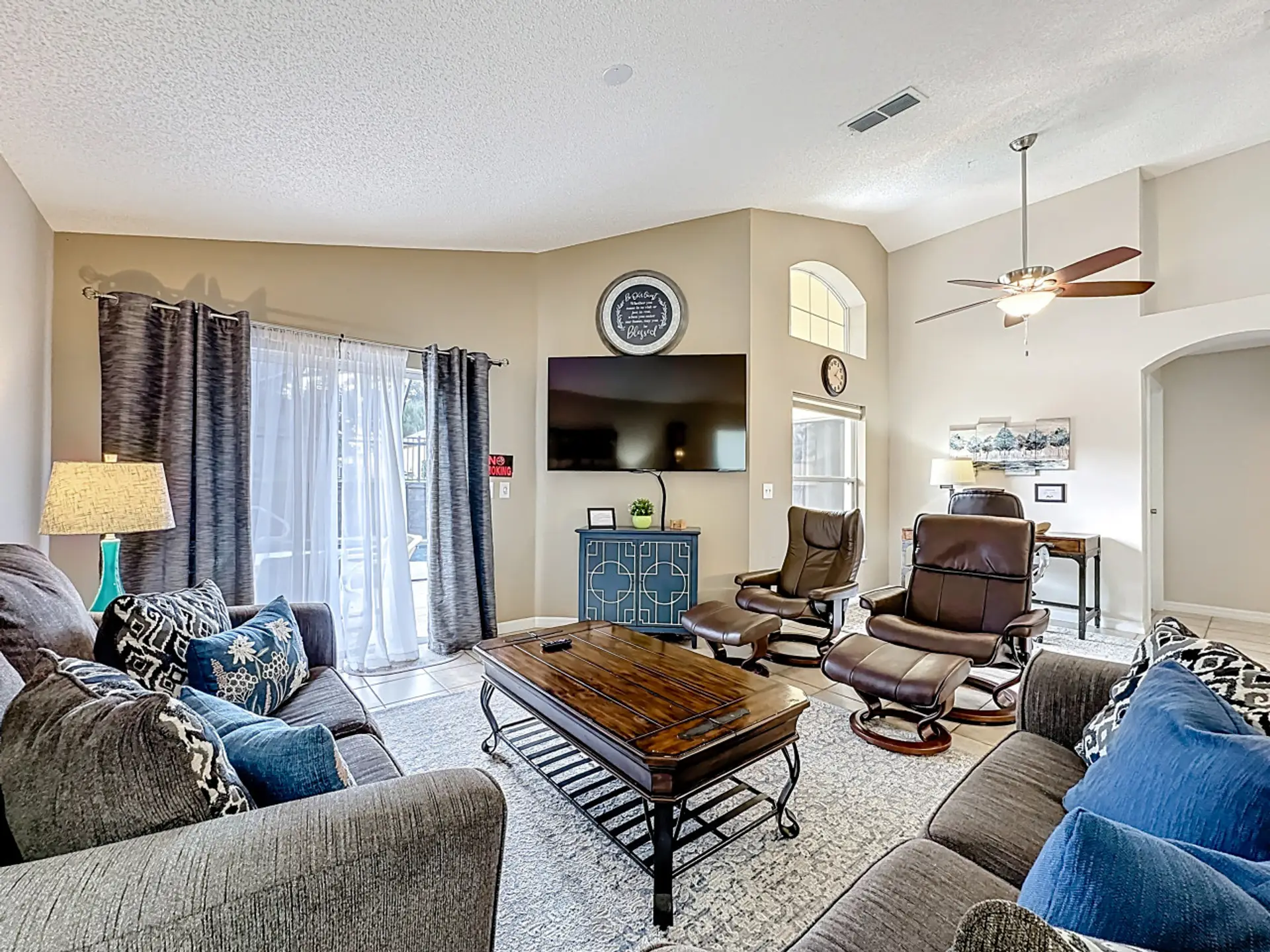 Spacious living room with comfortable seating, smart TV, and sliding glass doors leading to outdoor space.