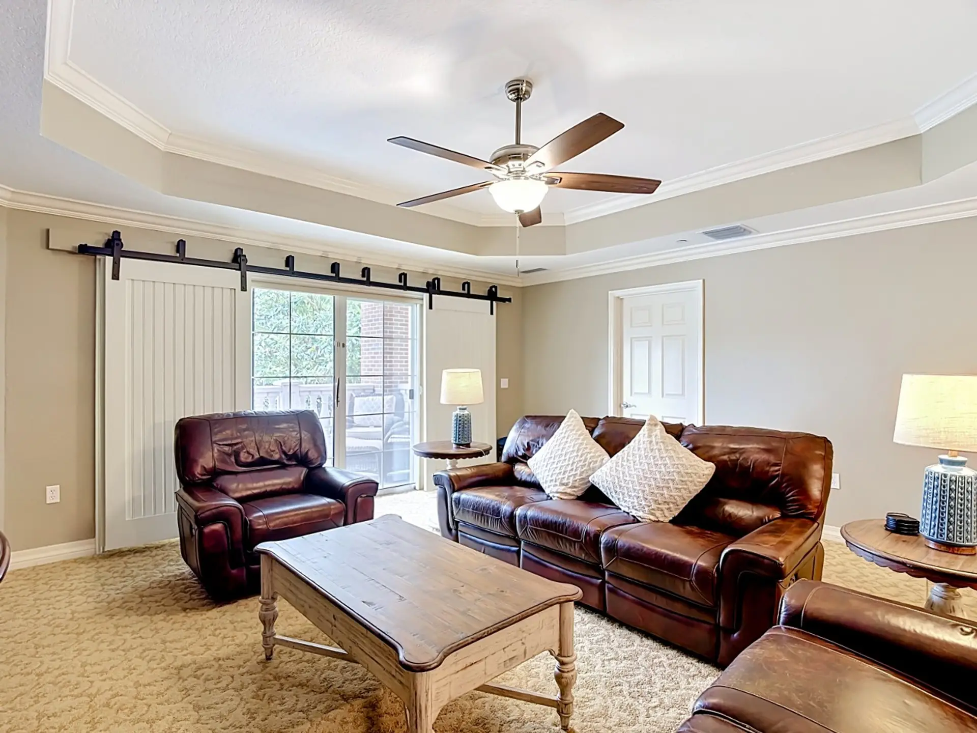 Spacious living room with leather seating, coffee table, and large windows providing plenty of natural light.