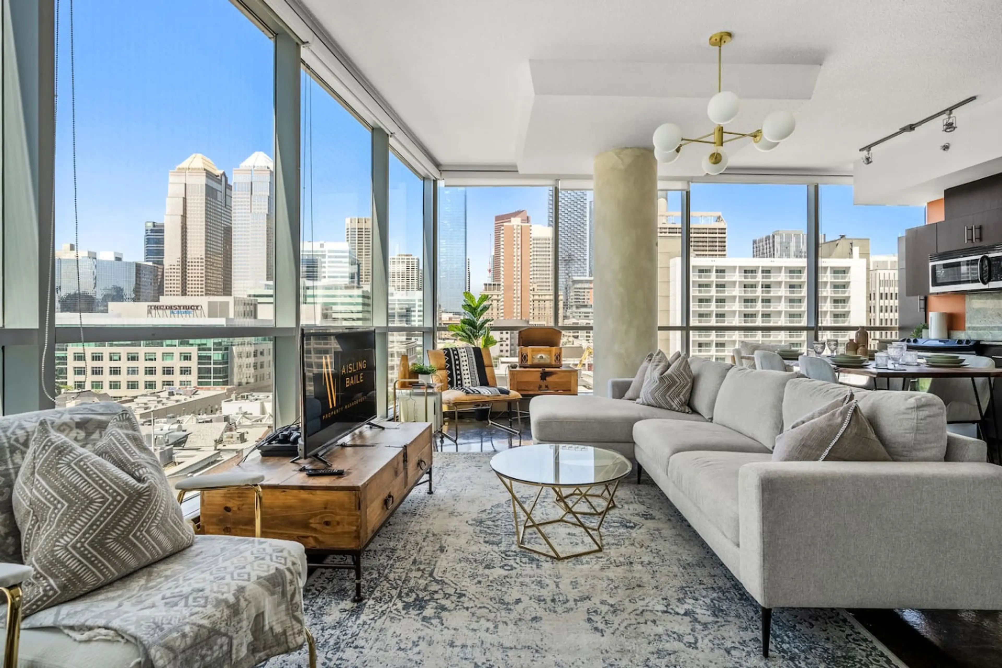 Living room with a 55" Smart TV, PS4, a record player and floor-to-ceiling, NW-facing windows with views of the Calgary tower & city skyline.