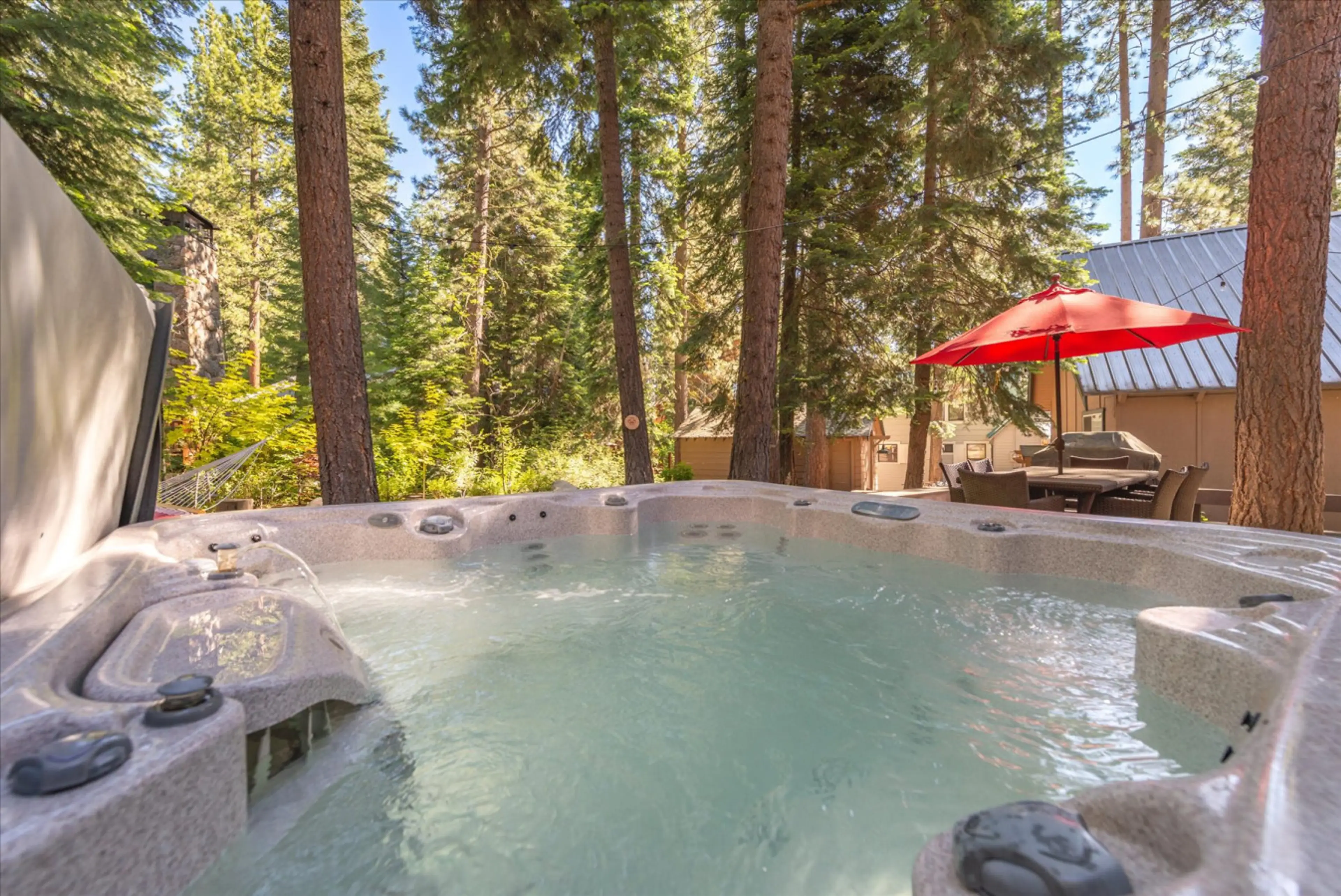 Beautiful landscaped backyard with knotty pine wood lounge chairs, a hammock, private hot tub and spacious deck with outdoor dining table and gas grill.